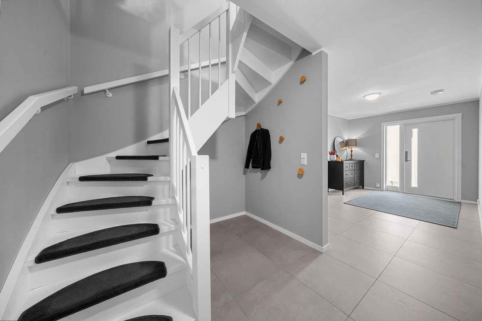 Et innbydende inngangsparti ønsker deg velkommen- innenfor døren blir man møtt av boligens entrè som har fliser på gulvet og gråmalte vegger. Det er god plass til skohylle og skap for oppheng av yttertøy. Galleribilde