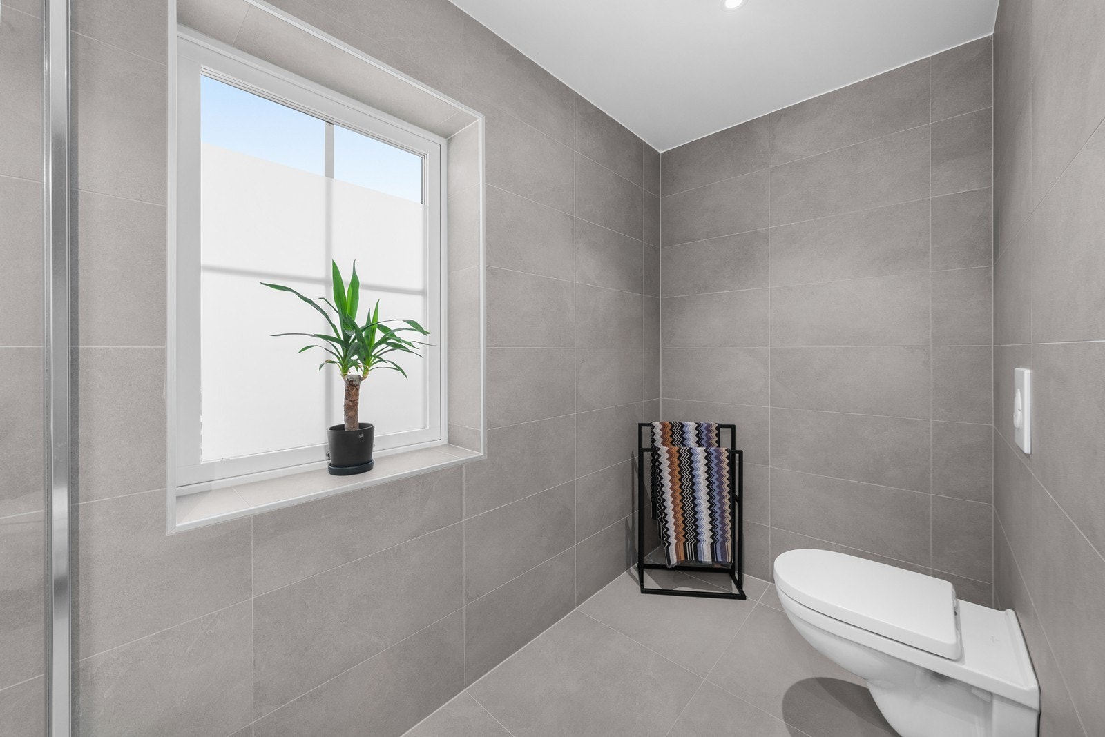 Det andre baderommet har fliser på gulv og vegger, sort servantinnredning med skuffeseksjon, dusjnisje med regnfallsdusj og skyvedør av glass og innebygd/vegghengt toalett. Galleribilde