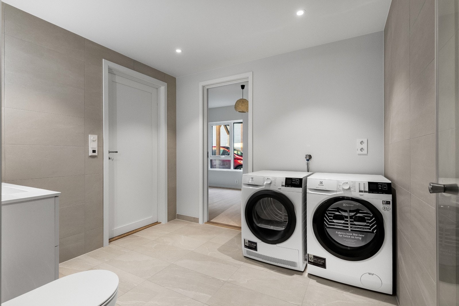 Badet har i tillegg et veggmontert toalett, samt dusjhjørne med regnfallsdusj, hånddusj og innfellbare glassdører. Det er avsatt plass til vaskemaskin på bad. Galleribilde