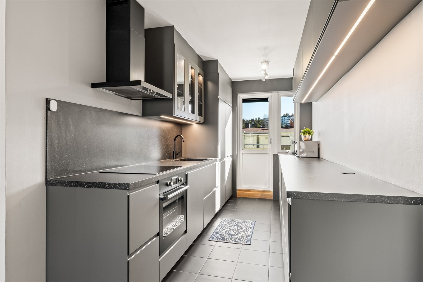 Stilrent og moderne kjøkken med integrerte hvitevarer, god arbeidsflate og utgang til balkong noe som gir rikelig med dagslys. Galleribilde