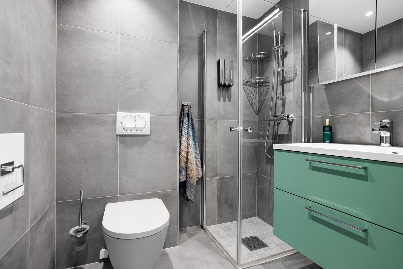 Vegghengt toalett, dusjnisje og baderomsinnredning med speil på vegg Galleribilde