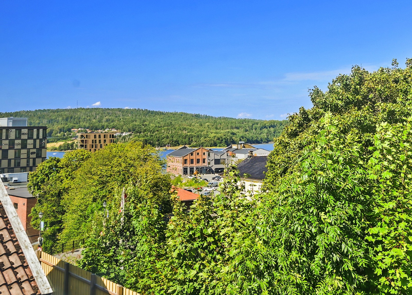 Mellom trær og bygninger ser man Mossesundet Galleribilde