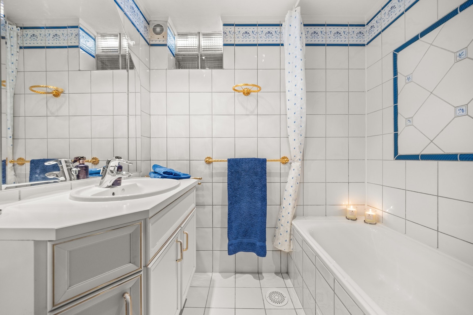 Flislagt bad med varme, nedfelt servant, dusjforheng og badekar Galleribilde