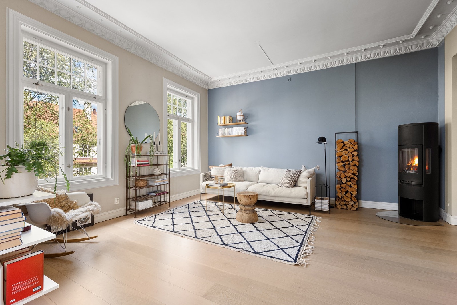 Høy takhøyde kombinert med klassisk stukkatur skaper en elegant ramme, mens peisovnen gir en lun og behagelig stemning på kjølige kvelder Galleribilde