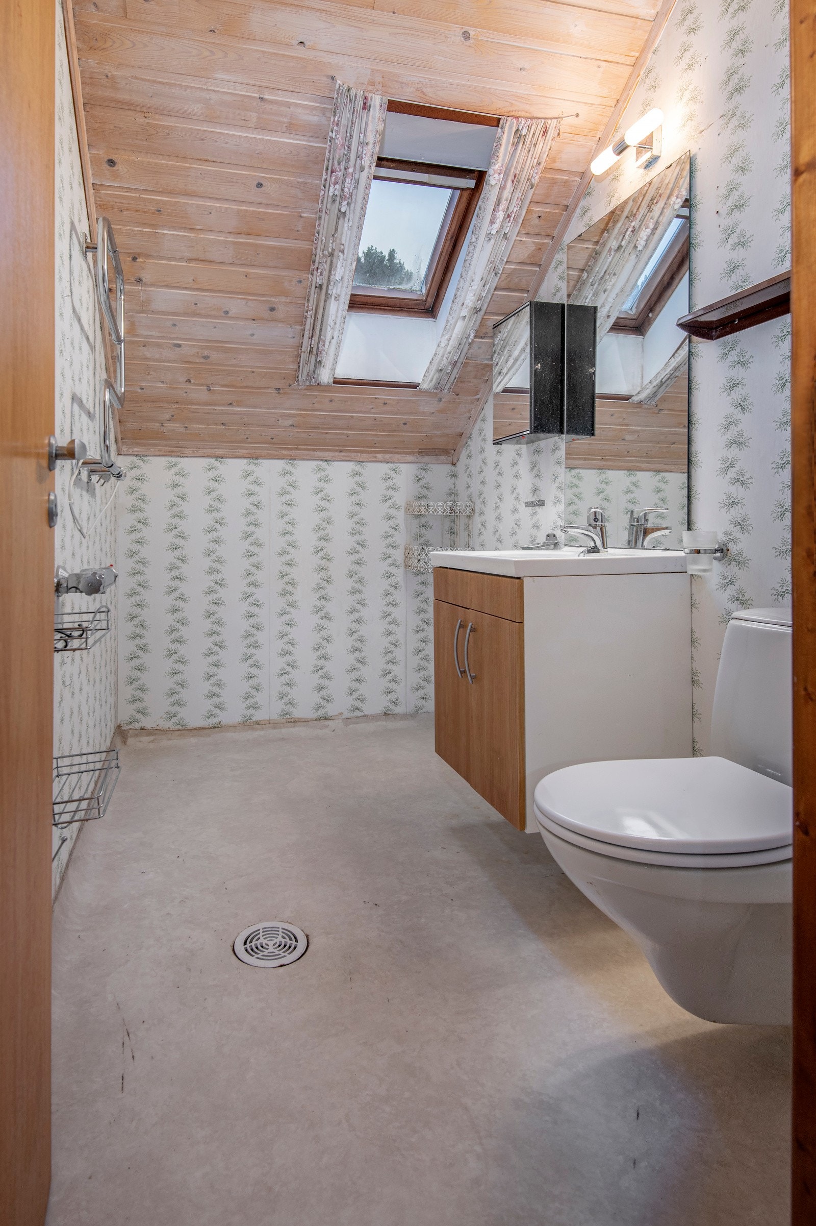 Toalettrommet på loftet har våtromsbelegg på gulvet, og tapet på veggene. Badet er utstyrt med vegghengt toalett, servantskap, og veggmontert stråleovn. Galleribilde