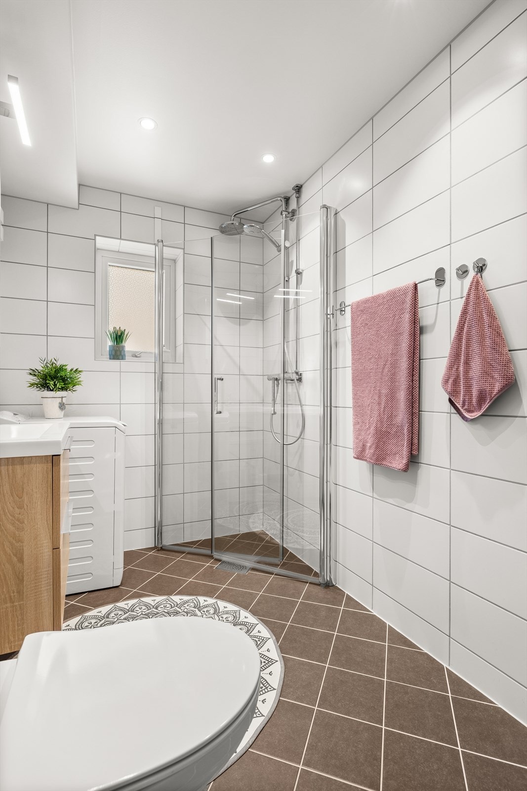 Badet har varmekabler i gulv, opplegg for vaskemaskin, toalett, servant med innredning og dujshjørne med innfellbare dusjdører Galleribilde