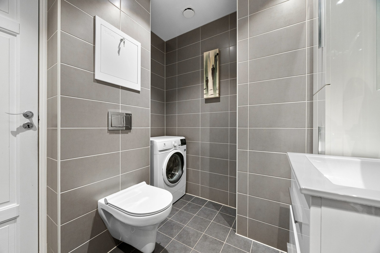 Flislagt bad med varmekabler i gulv og opplegg for vaskemaskin. Galleribilde