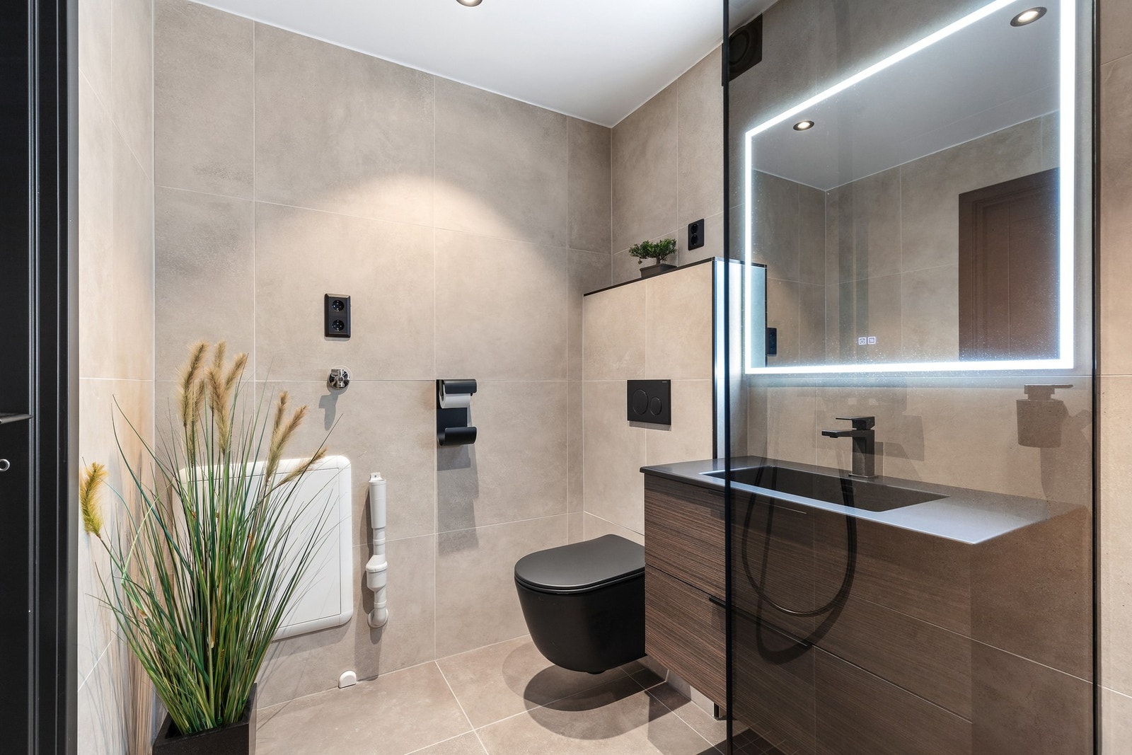 Rommet har innredning med nedfelt servant, veggmontert toalett, dusjhjørne og opplegg for vaskemaskin Galleribilde