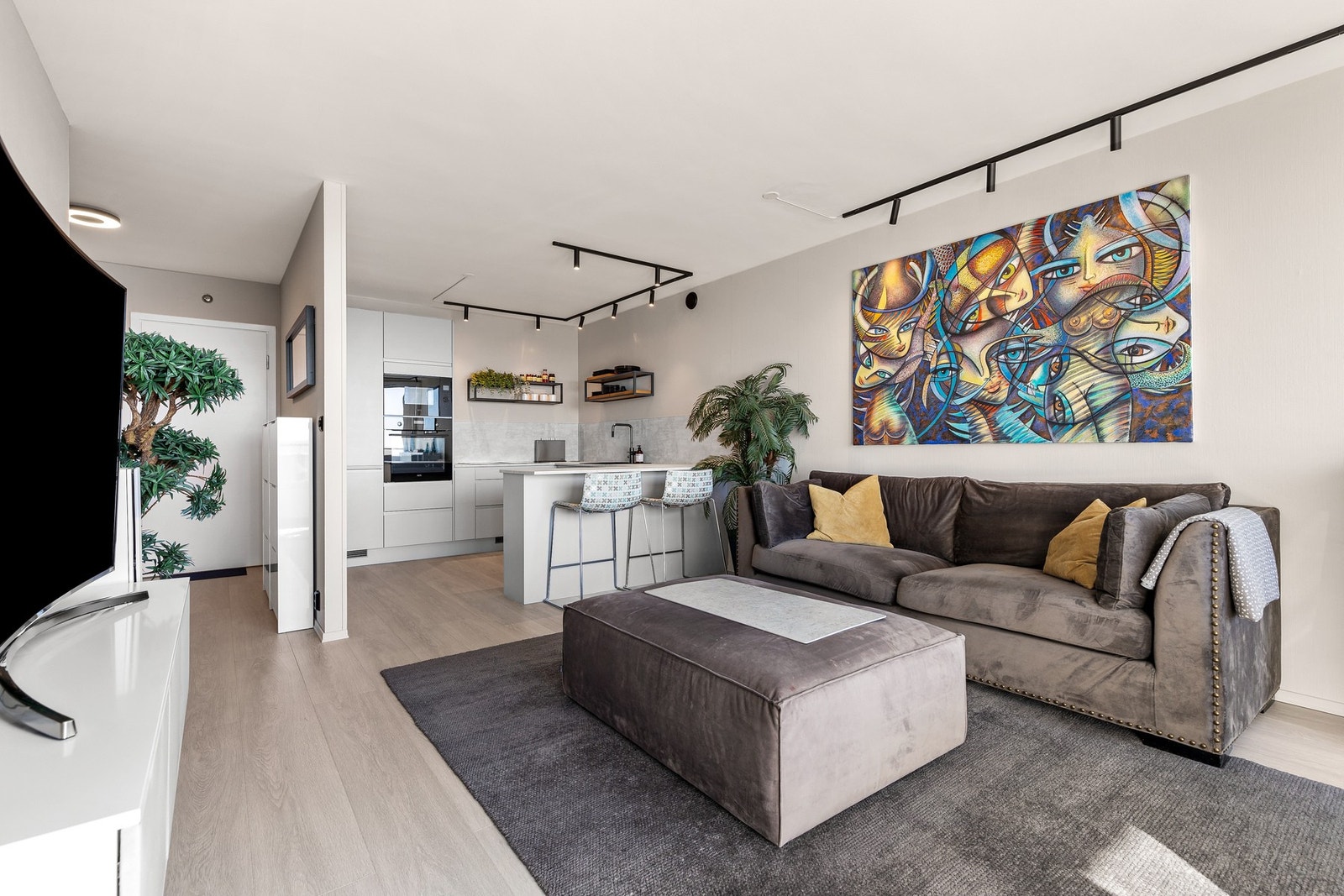 En stilren kjøkkenøy med barløsning skaper en naturlig overgang mellom kjøkken og stue. Galleribilde