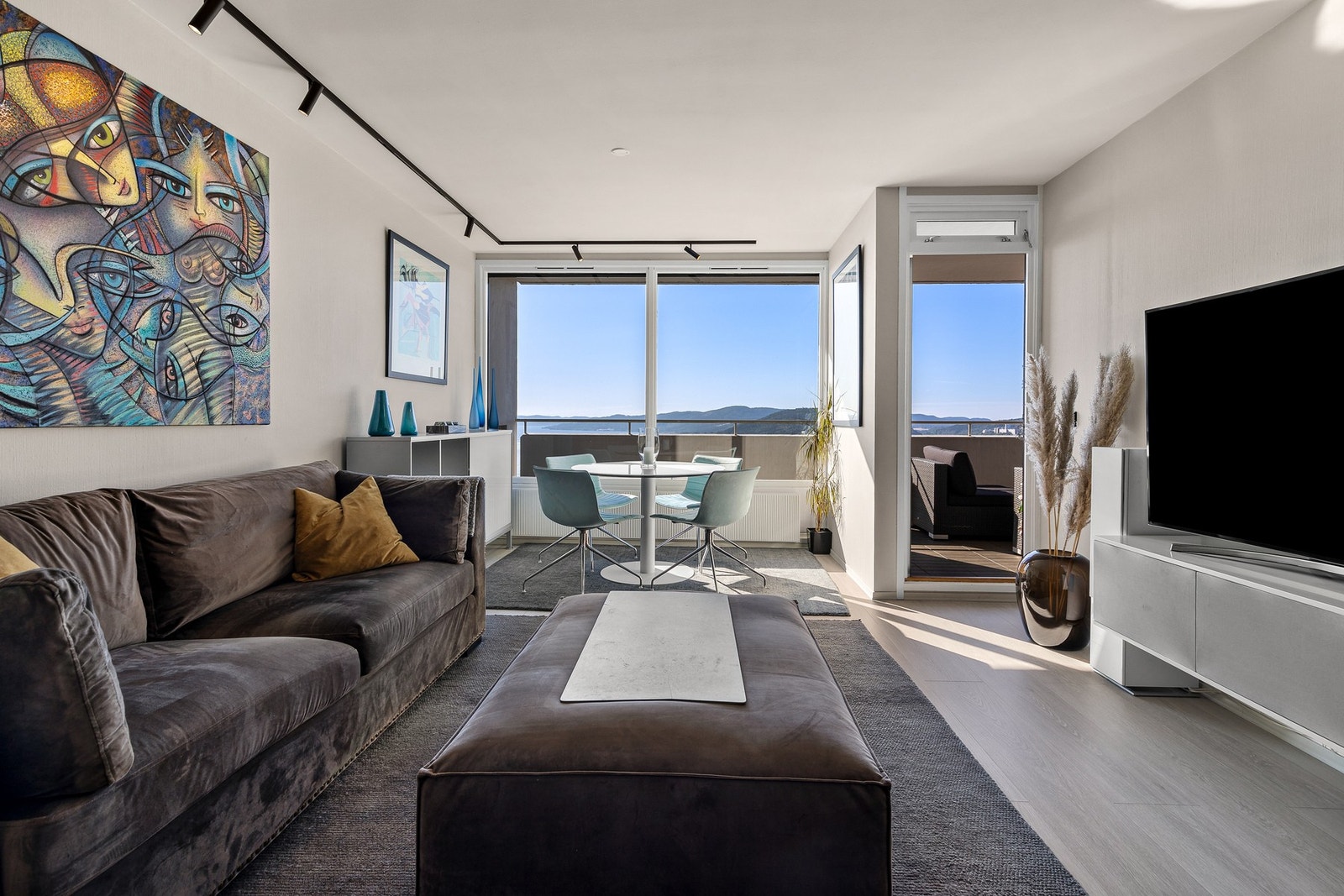 Lys og tiltalende stue med 1-stavs laminatgulv og malt tapet på vegger, samt spotskinner i himling Galleribilde