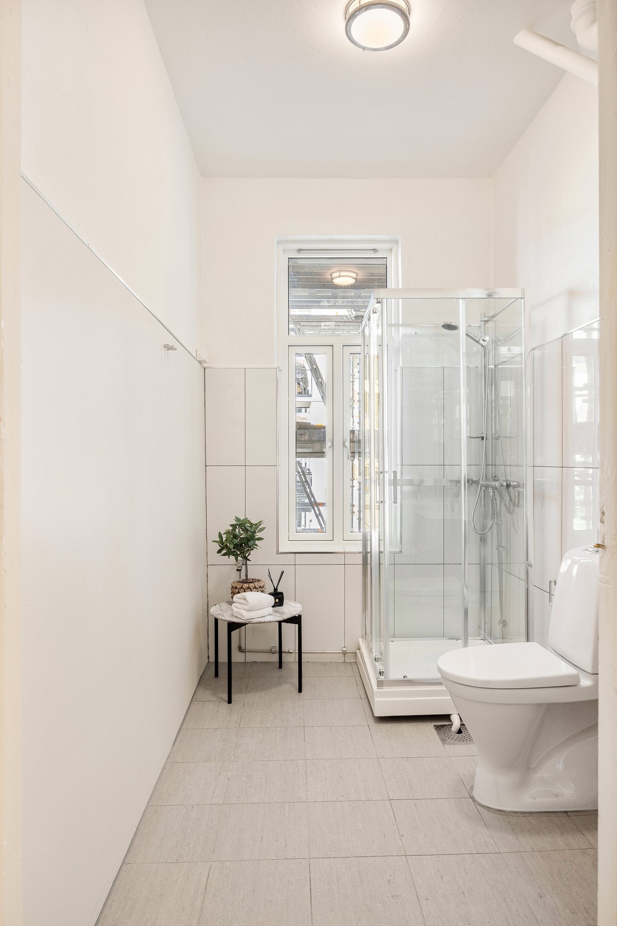 Stort baderom med lyse overflater og vindu. Galleribilde