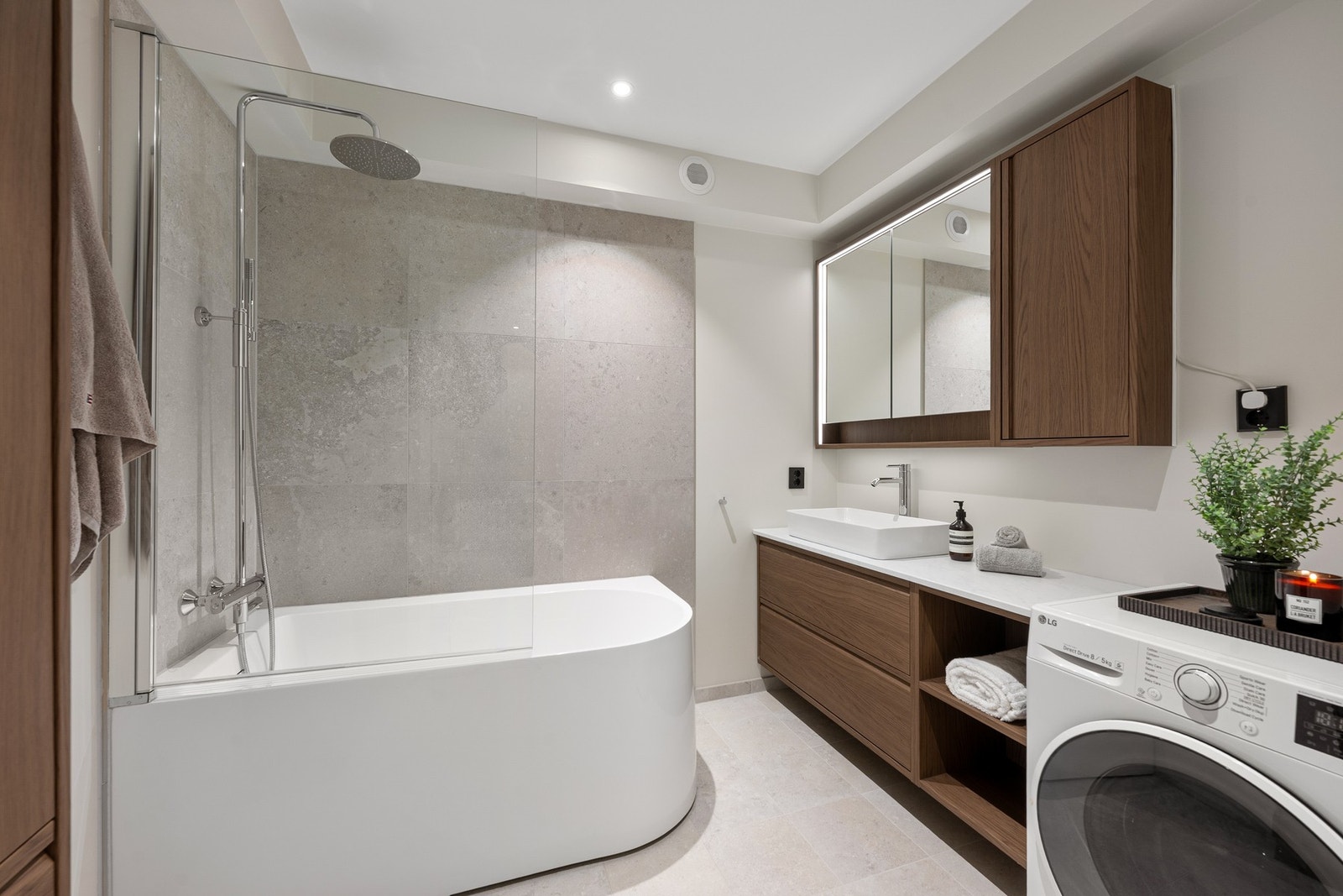 Moderne, lekkert og funksjonelt vaskerom/bad med delikat badekar og opplegg for vaskemaskin og tørketrommel. Galleribilde