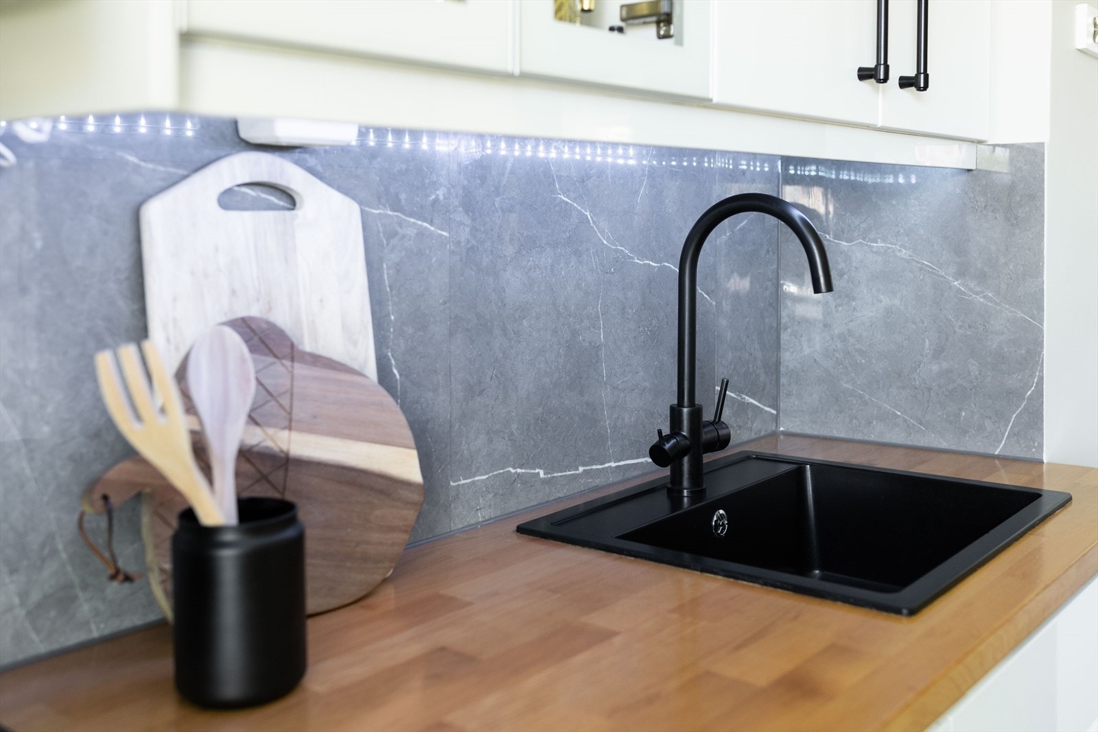 Innredningen består av hvite, slette fronter, fliser på bakvegg og laminert benkeplate med nedfelt oppvaskkum Galleribilde