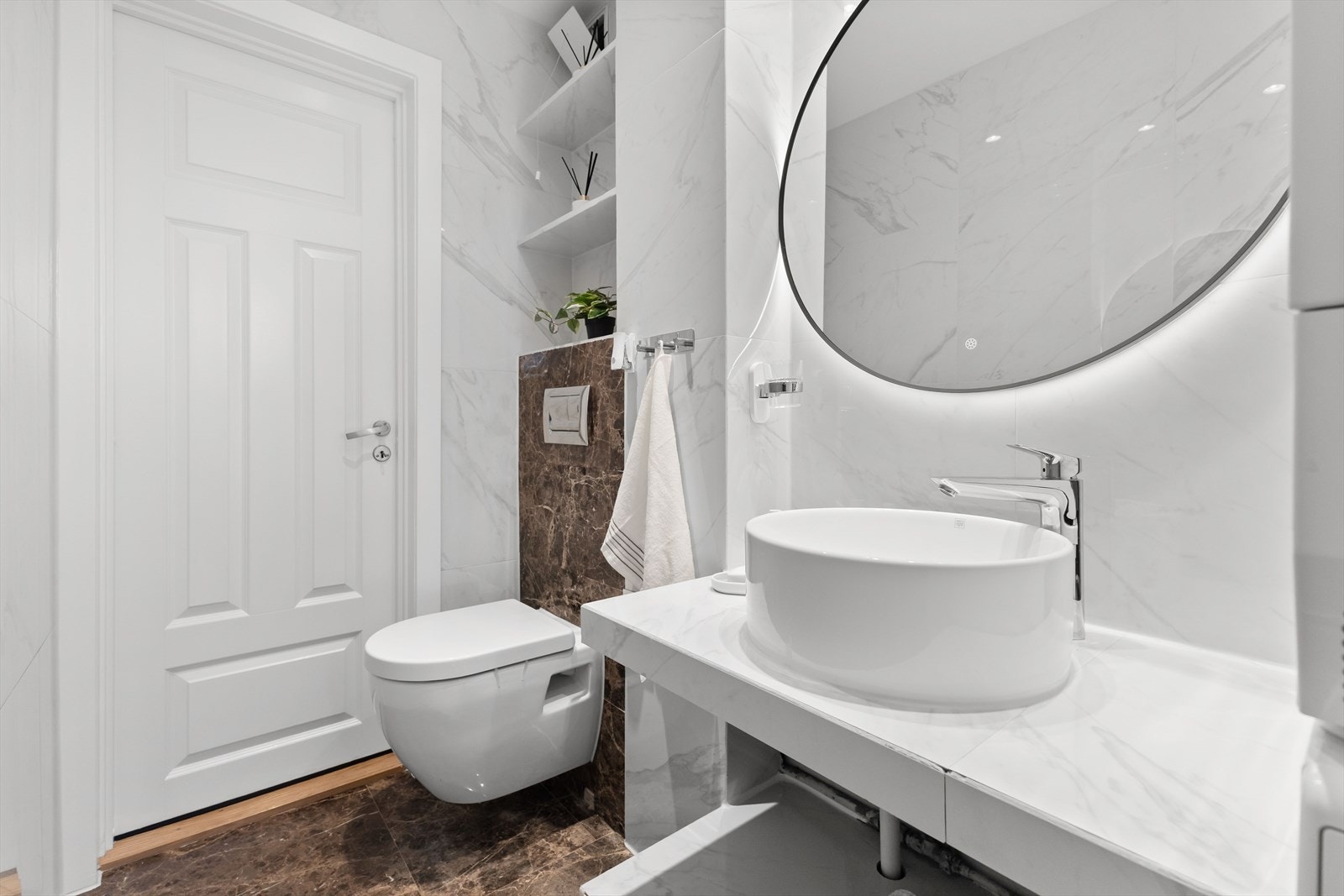 Baderomsinnredningen består av servant med hylleseksjoner, vegghengt toalett og dusjhjørne med glassdør. Galleribilde