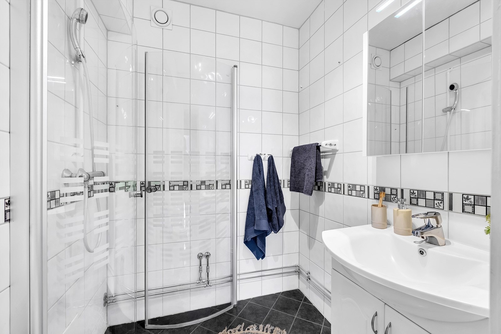 Badet er innredet med sorte gulvfliser og hvite fliser på veggene. Galleribilde