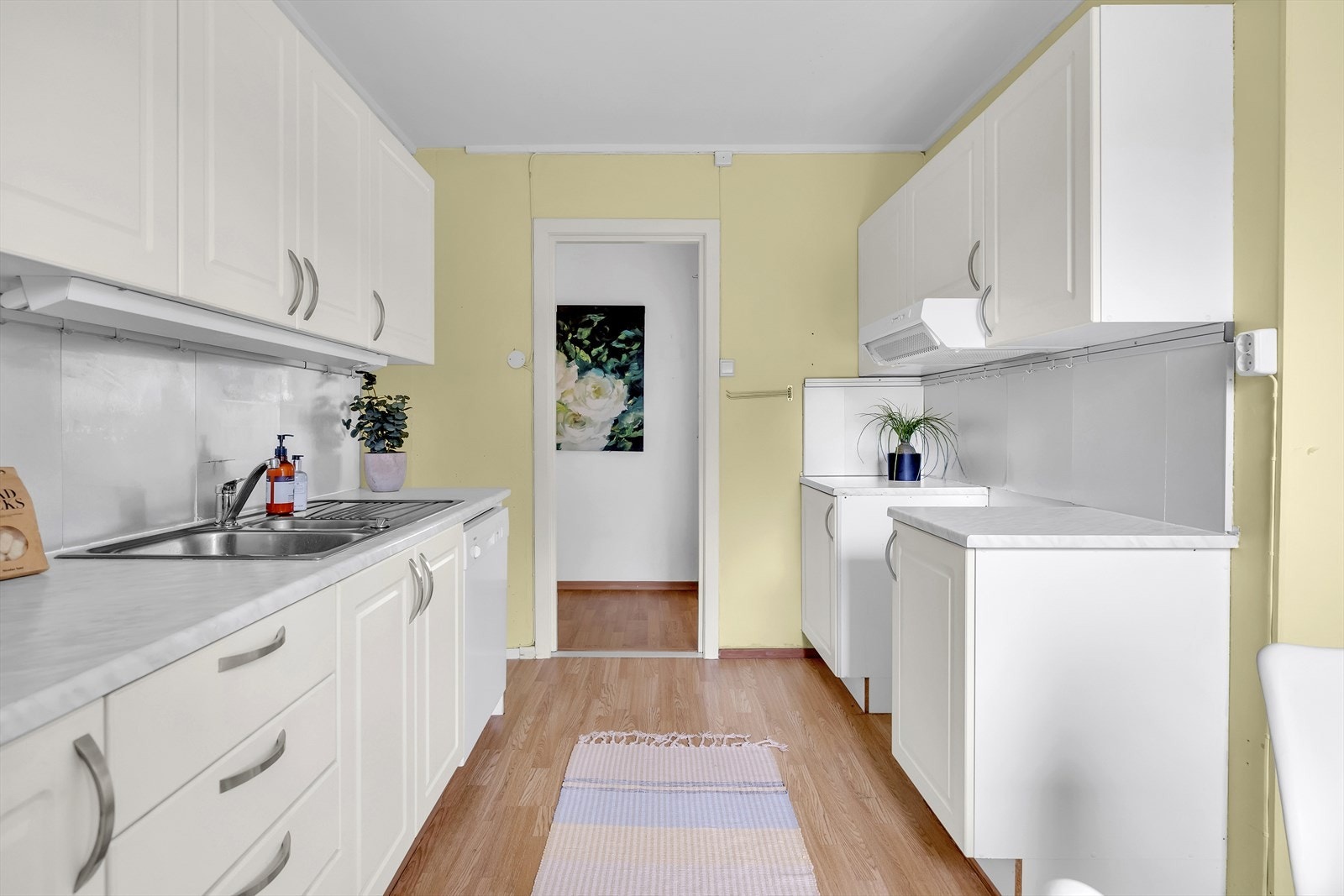 Innredningen har hvite, profilerte fronter, oppvaskmaskin, dobbel oppvaskkum og lys benkeplate av laminat. Galleribilde
