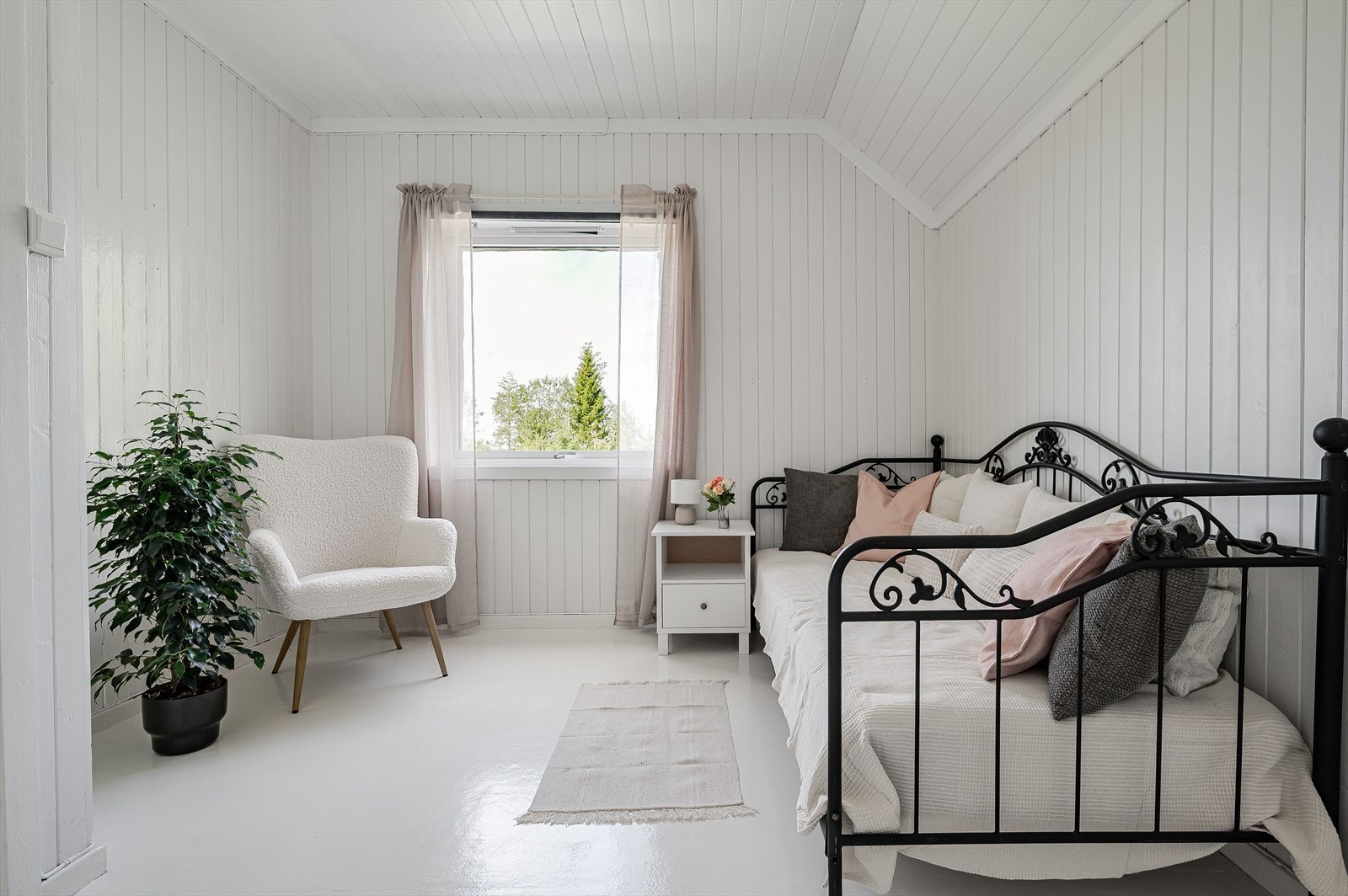 I andre etasje er det to soverom, der det ene er lysmalt på alle overflater og virkelig byr på den landlige stilen. Legg merke til den gamle, smale panelen. Galleribilde