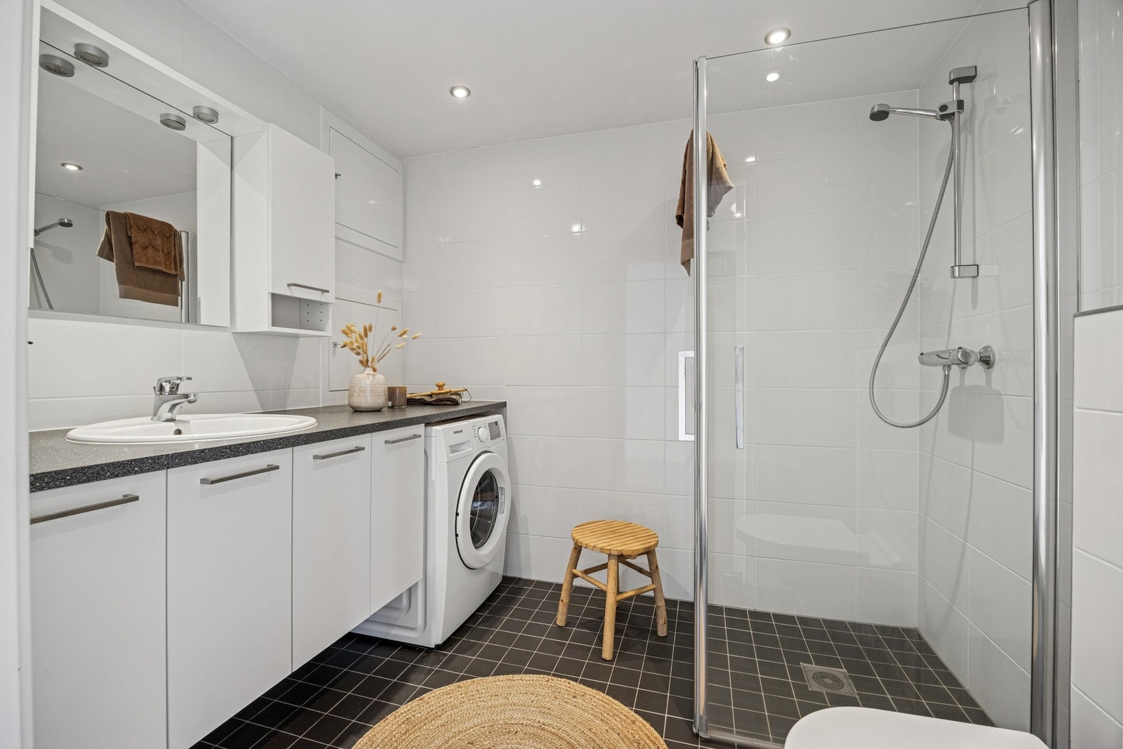 Moderne baderom med gulvvarme, servantskap, mekanisk avtrekk, opplegg for vaskemaskin, veggmontert wc og innfellbare dusjdører. Galleribilde