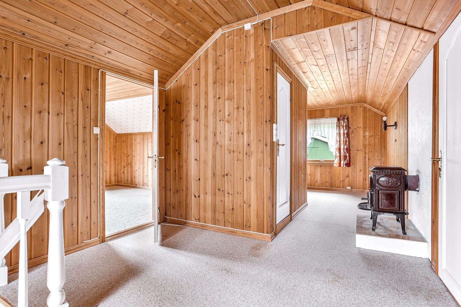 Loftstuen har teppelagt gulv, trepanel på veggene og en vedovn. Galleribilde