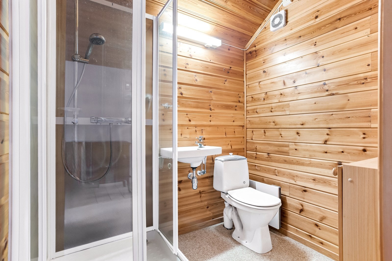 Badet i andre etasje har toalett og dusjkabinett, samt en enkel servant med tilhørende lys over. Gulvet er teppelagt, mens veggene har trepanel. Galleribilde