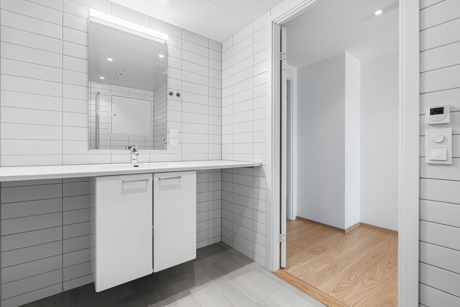 Innredningen består av en heldekkende servant på hvit innredning med to skapdører av slette fronter. Galleribilde