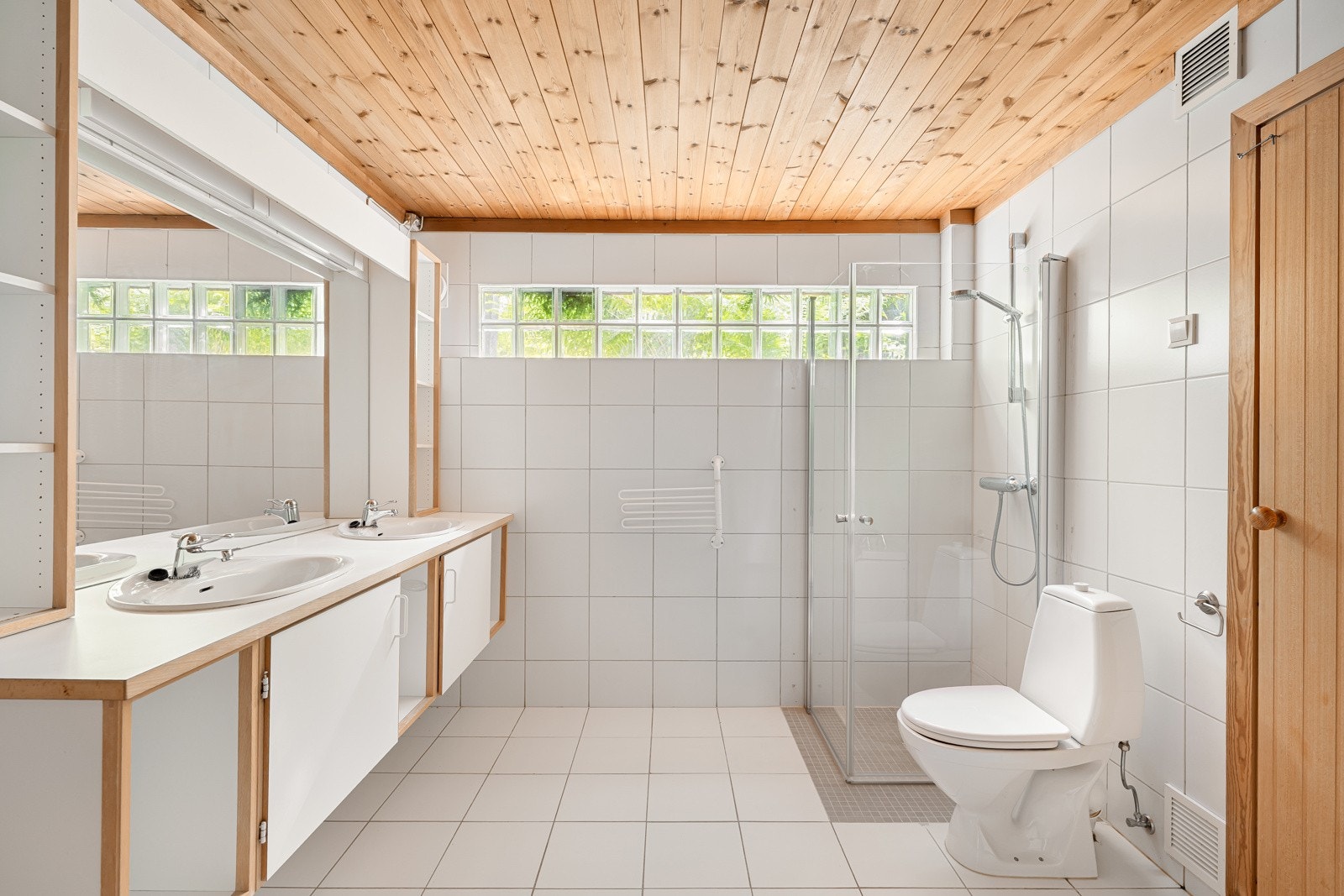 Stort og flislagt baderom. Innredet med seksjon med dobbel servant, hjørnekar, dusj med glassdører og toalett. Galleribilde