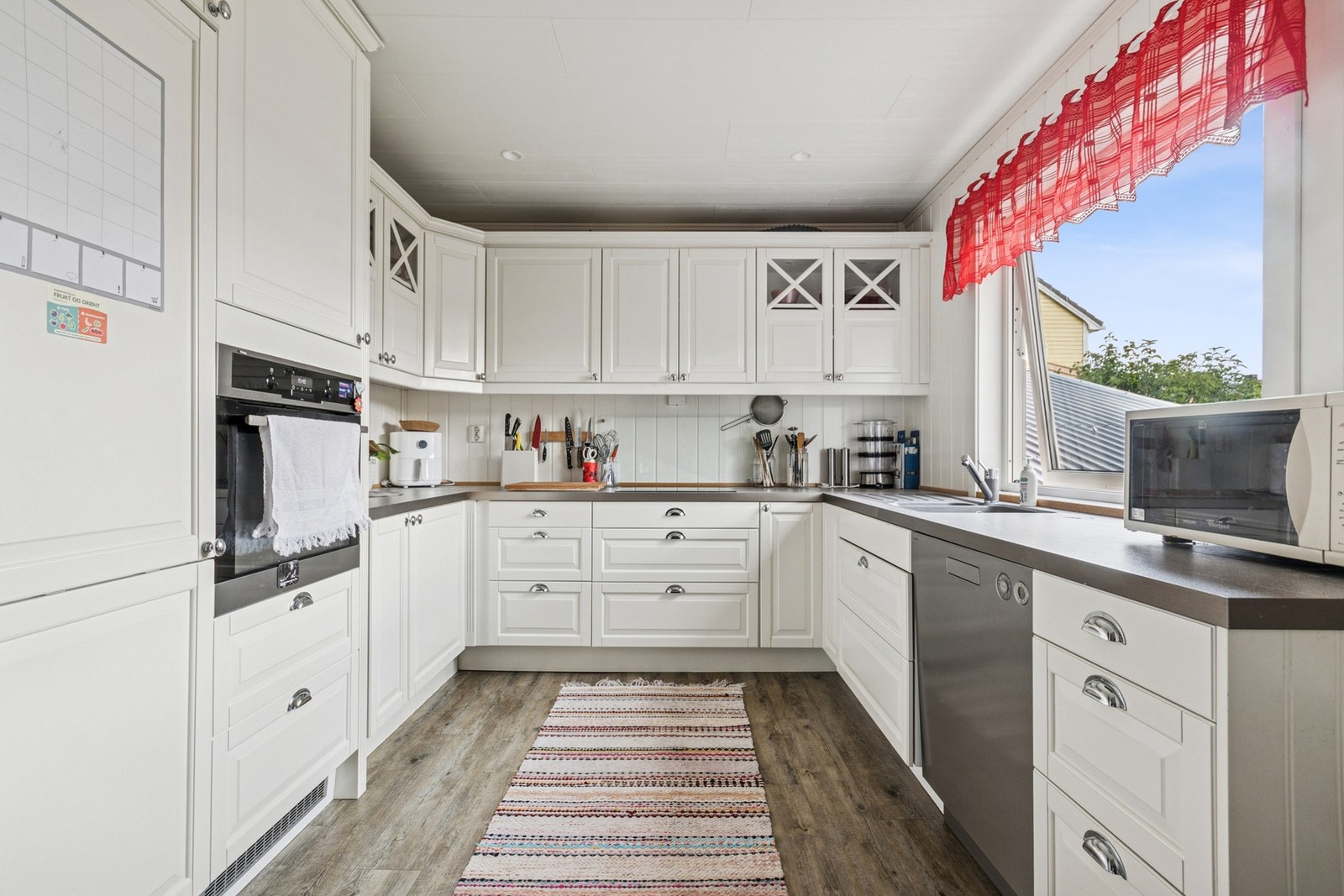 Kjøkken i tidløs utførelse med hvite profilerte kjøkkenfronter og benkeplate i laminat. Galleribilde