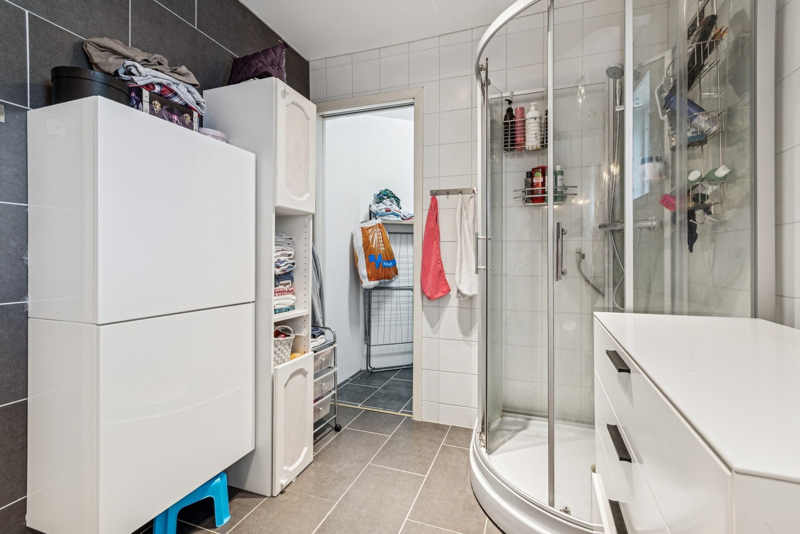 Badet er innredet med nedfelt servant, veggmontert toalett, dusjkabinett og opplegg for vaskemaskin. Galleribilde