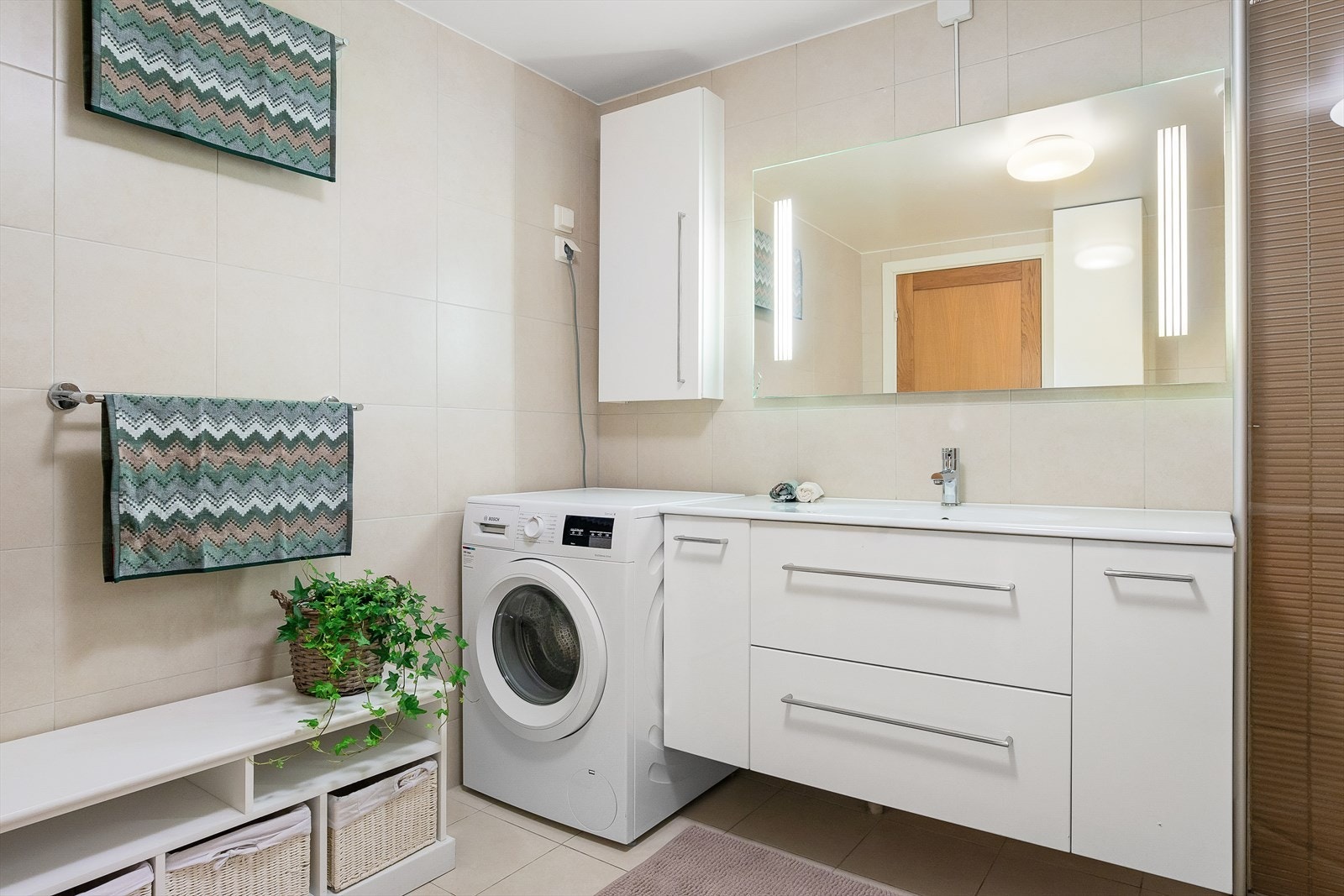 Badet har opplegg for vaskemaskin/tørketrommel ved siden av servant. Galleribilde