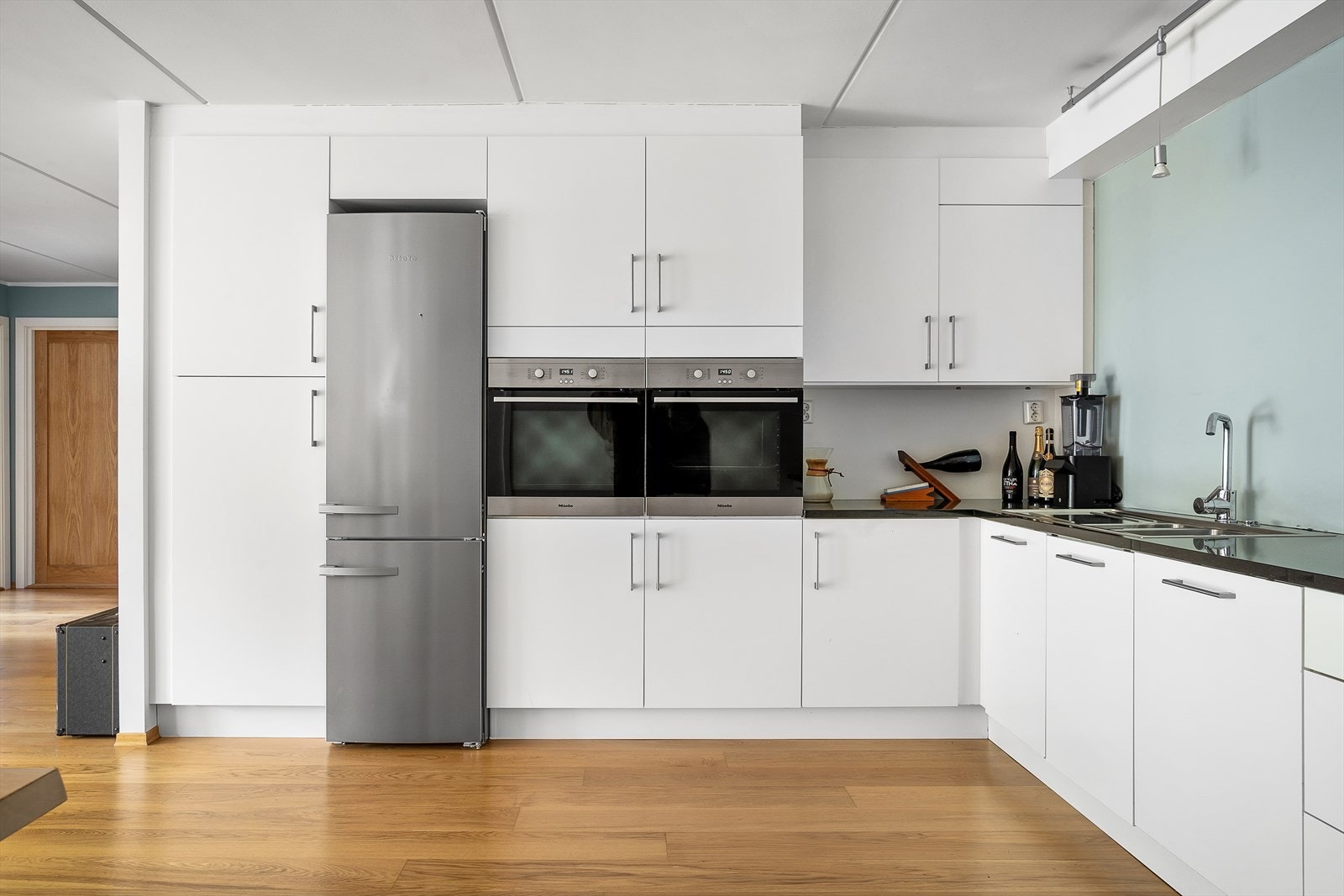 Opplegg for frittstående kjøleskap med fryser, integrert oppvaskmaskin og to stekeovner fra Miele, samt induksjonstopp fra Siemens. Galleribilde