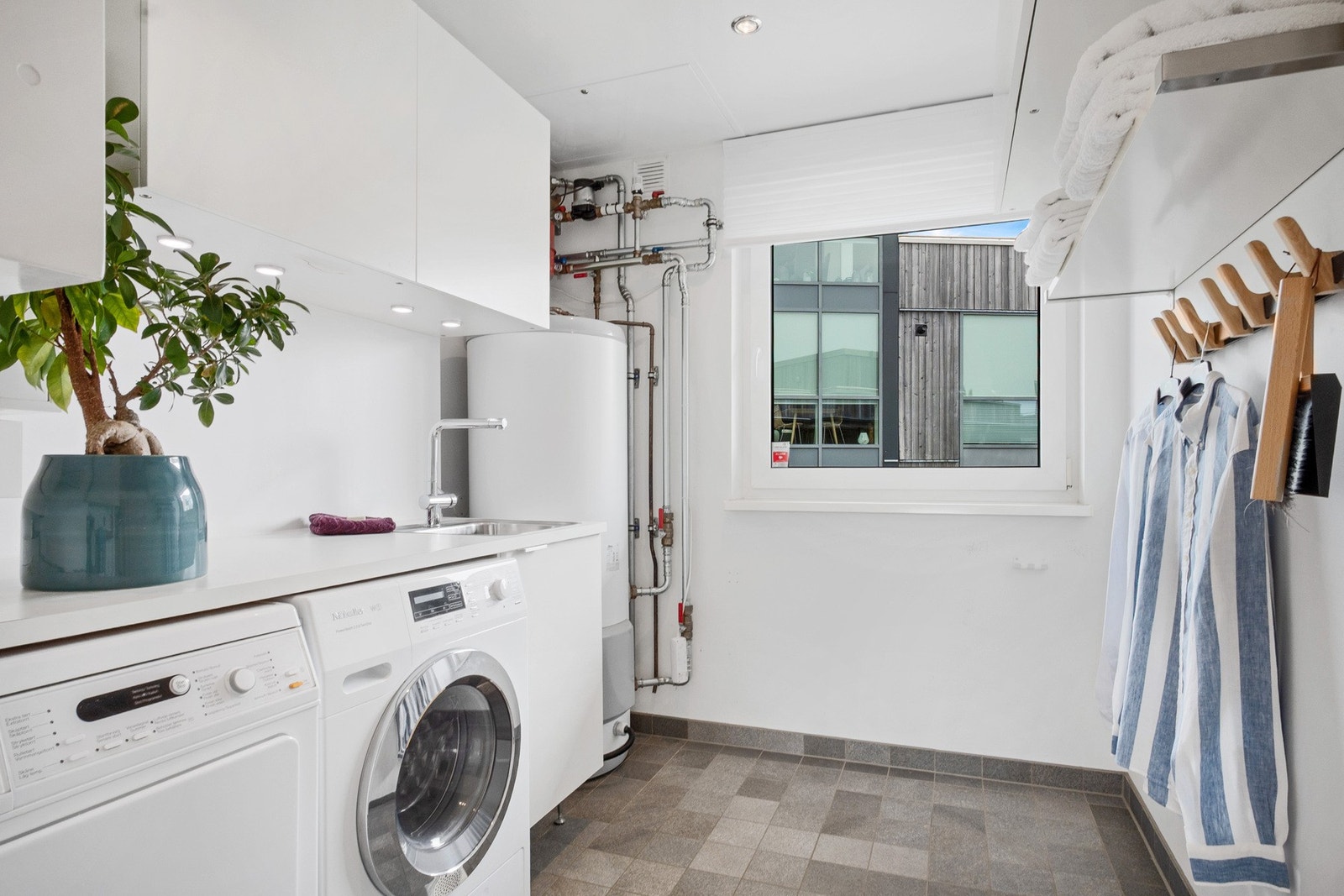 Praktisk vaskerom med innredning, vaskekum og opplegg for vaskemaskin Galleribilde