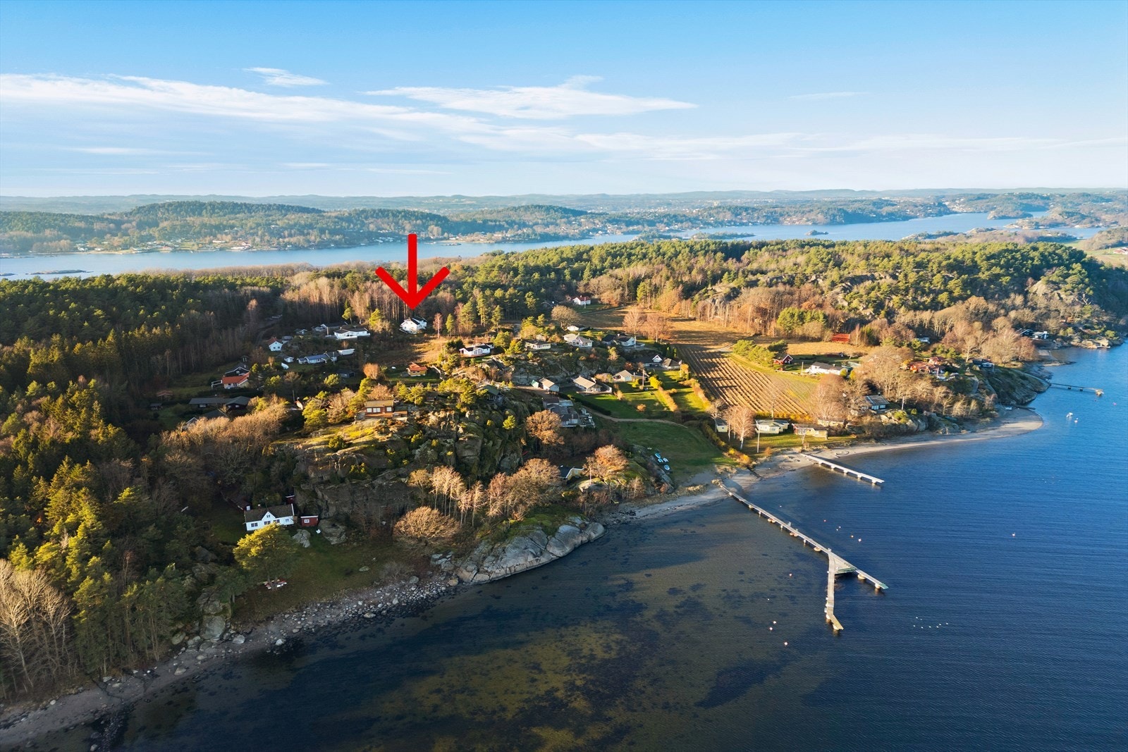 Dette dronebildet viser den unike beliggenheten til Tallakshavn 47, kun 250 meter i luftlinje fra sjøen. Her ser du hvordan boligen ligger på en solrik og tilbaketrukket tomt, omkranset av vakker natur og med enkel tilgang til både strand og felles brygge Galleribilde