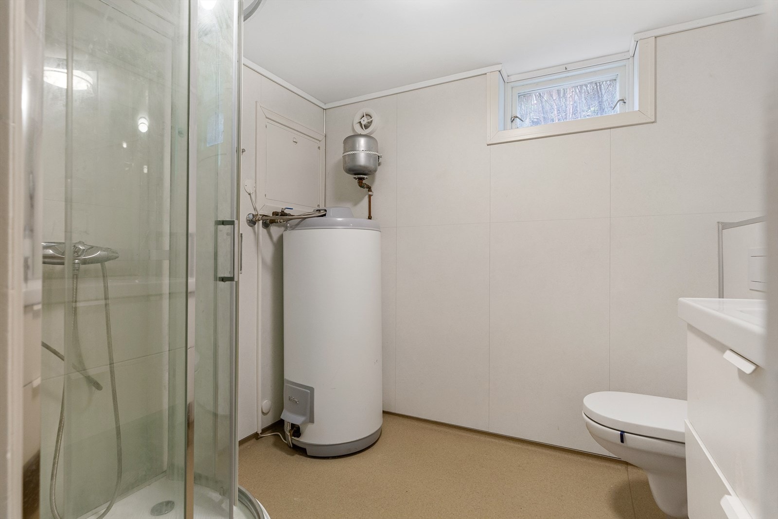 Badet er utstyrt med innredning med hvite glatte fronter med servant, dusjkabinet og wc. Galleribilde