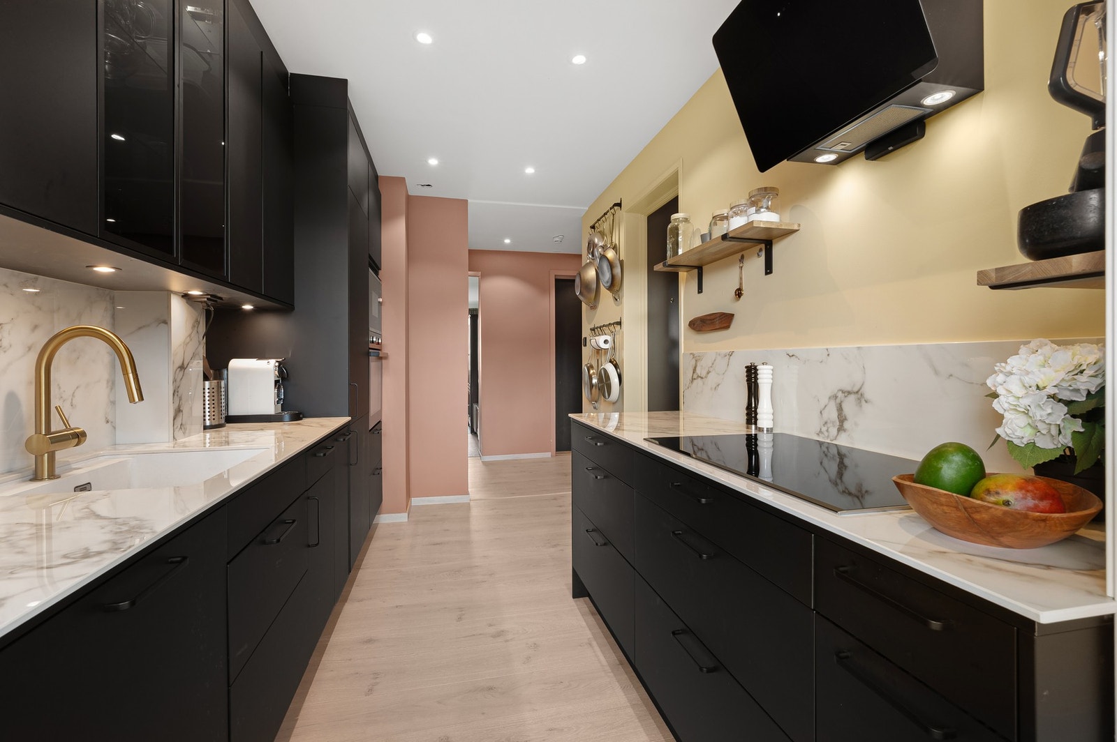 Stilrent og påkostet kjøkken med keramisk benkeplate og matchende keramisk backsplash på begge sider. Galleribilde