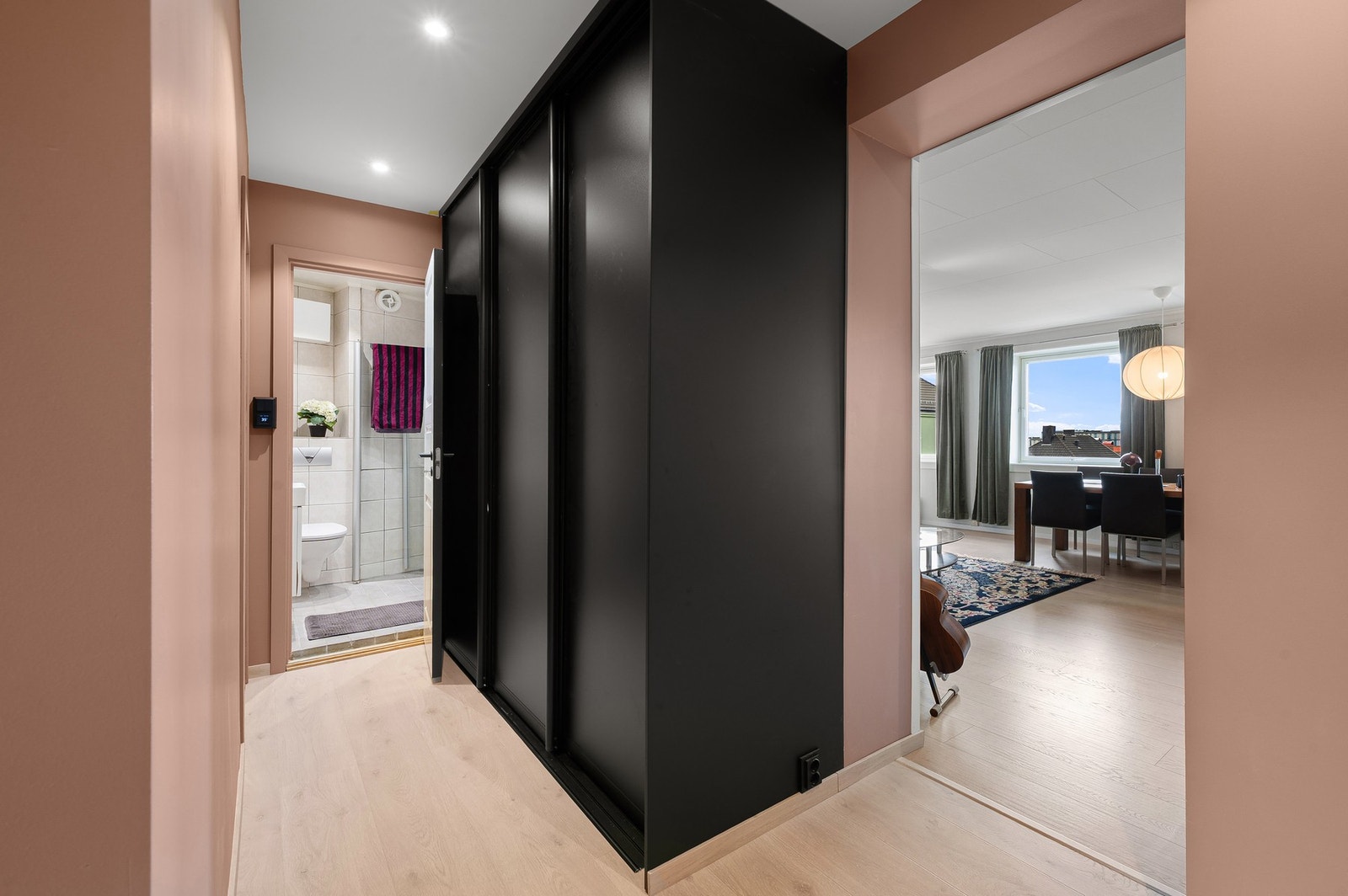 Stilren gang med plassbygd skyvedørsgarderobe som gir rikelig oppbevaringsplass og et ryddig uttrykk. Inne i garderobeløsningen er det etablert plass til vaskemaskin. Galleribilde