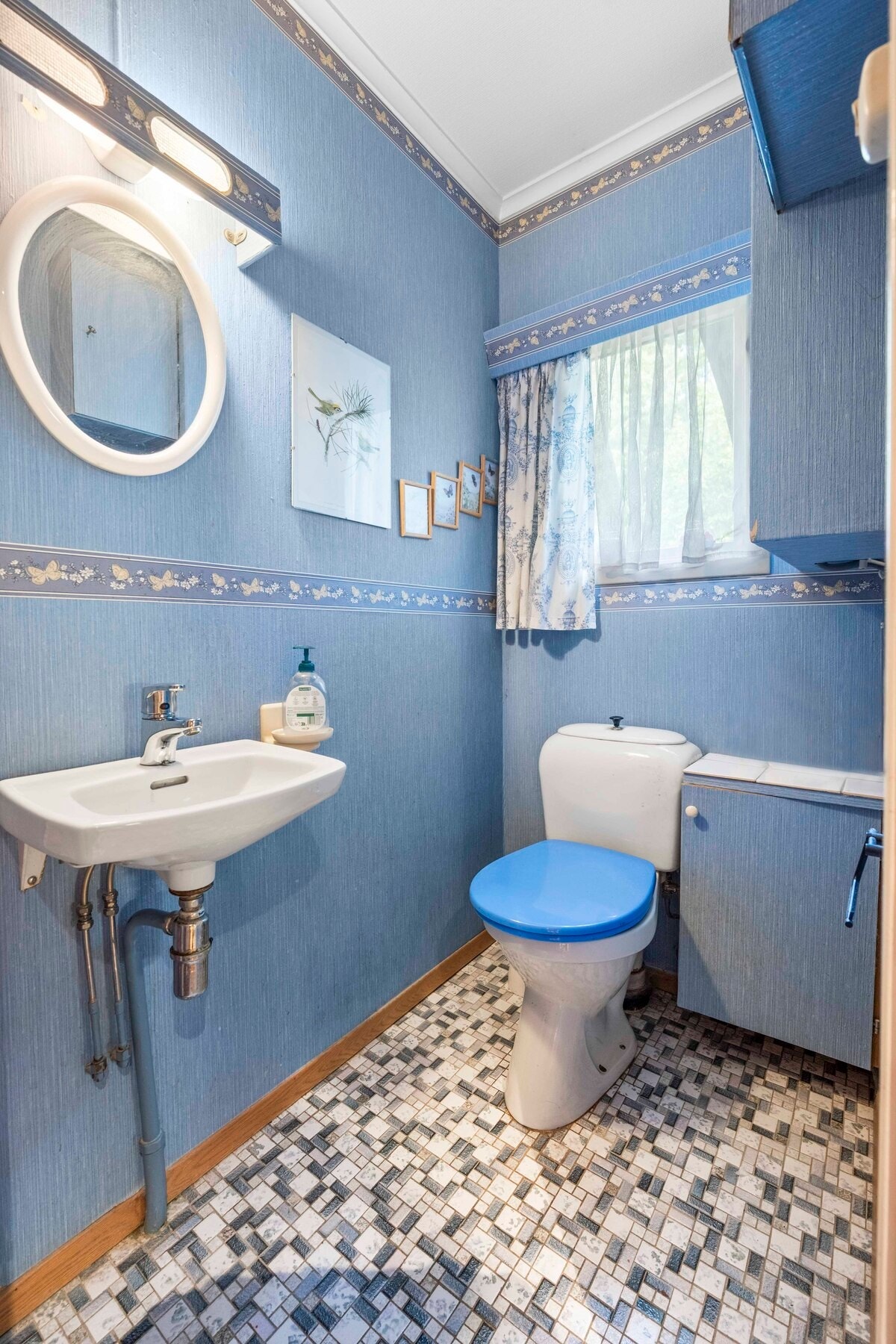 Toalettrom fra byggeår, med flislagt gulv og vegger med tapet. Galleribilde