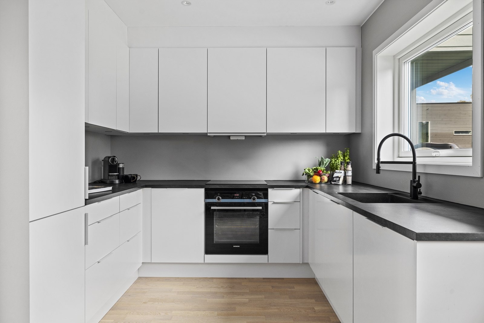 Tidsriktig innredning fra 2023 med hvite, slette fronter og benkeplate i laminat. Galleribilde