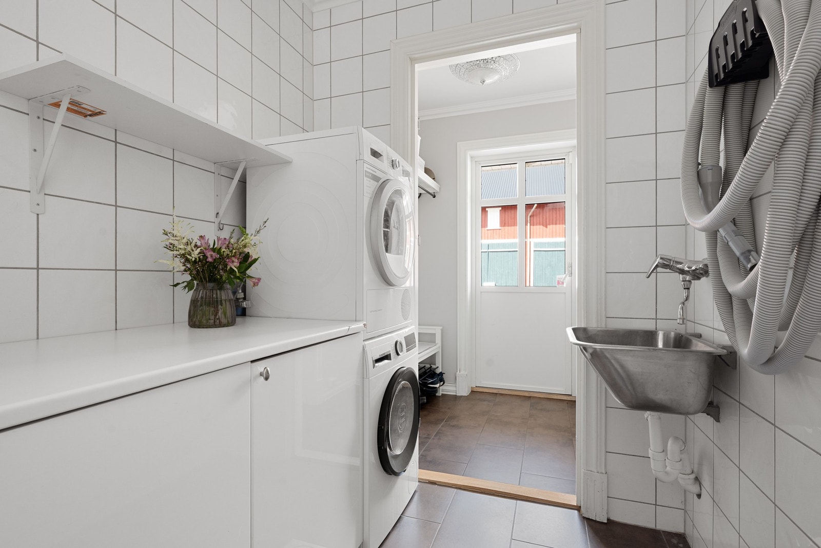 Eget vaskerom med flislagt gulv og gulvvarme. Rommet har innredning, utslagsvask samt opplegg for vaskemaskin og tørketrommel - perfekt plassert for en aktiv familie. Galleribilde