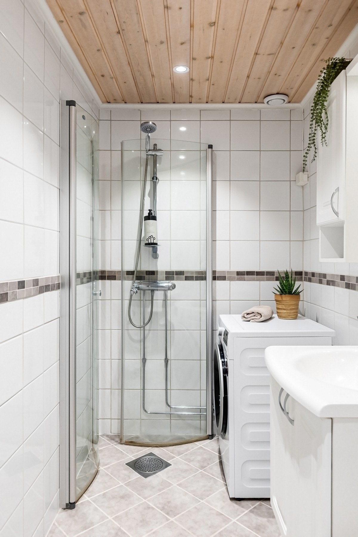 Bad med flislagte vegger og gulv, og panel i taket med downlights. Galleribilde