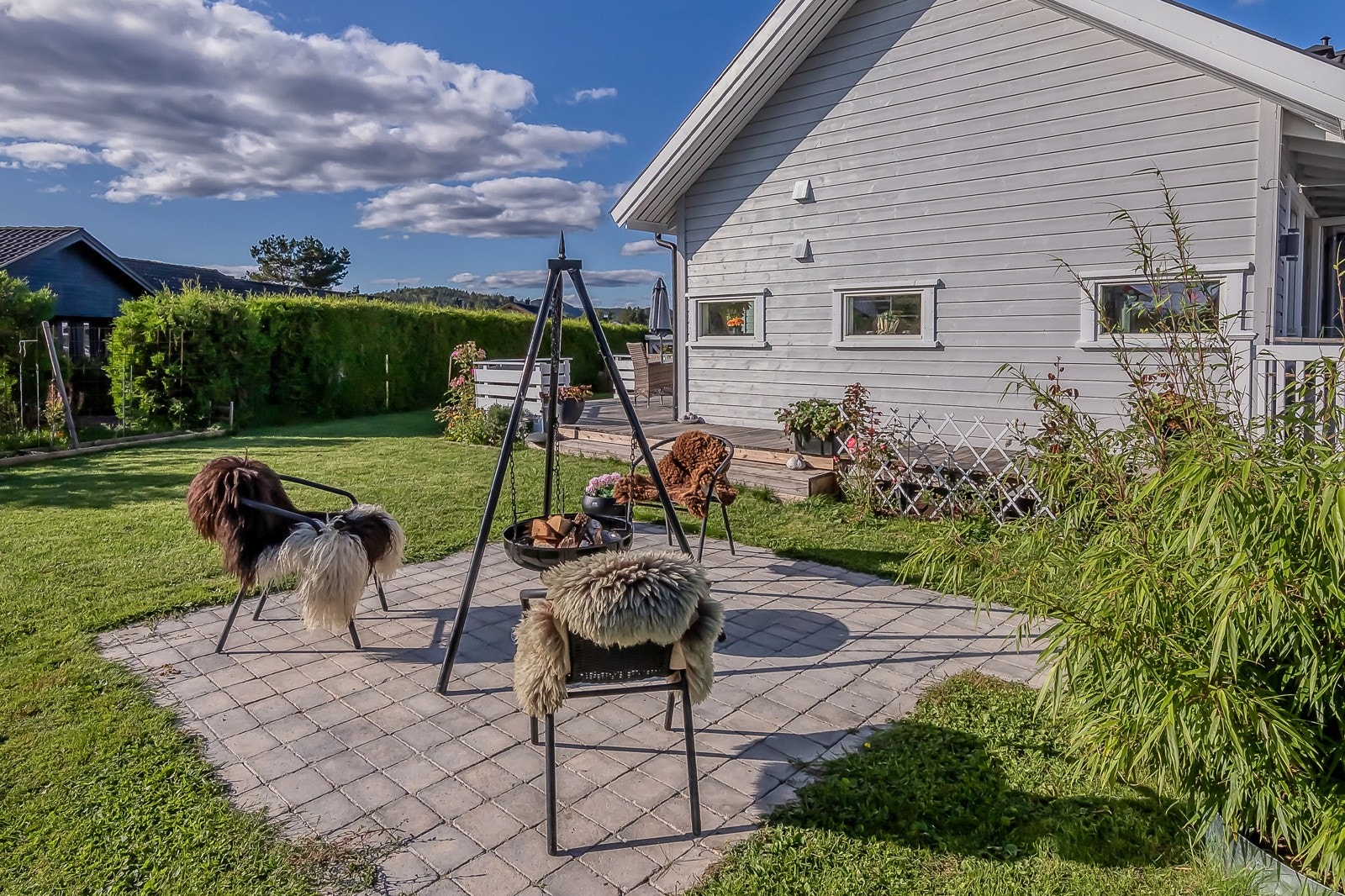 Fin steinbelagt uteplass i hagen. Sett herfra går solen går ned til venstre for boligen. Galleribilde