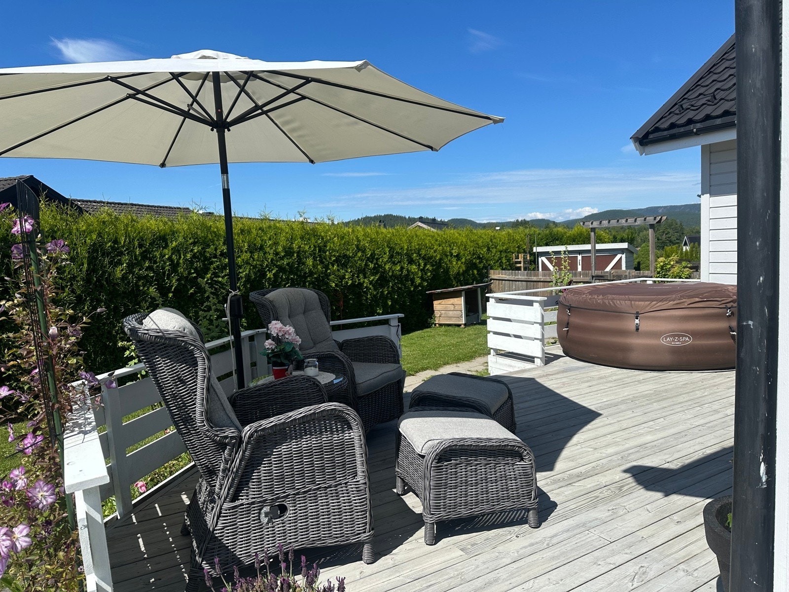 Fin vestvendt uteplass med dør ut fra stuen. Nåværende eier har et boblekar på terrassen. Solen går ned over fjellene i horisonten. Galleribilde