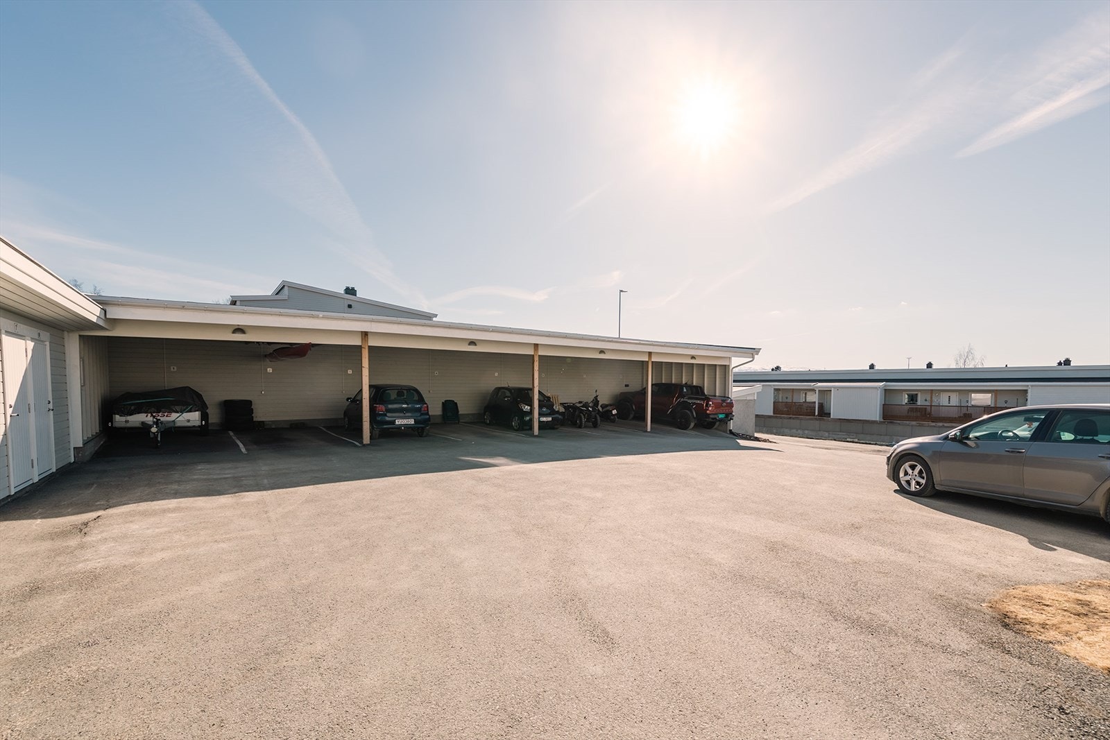 Asfaltert gårdsplass. Hver leilighet disponerer utebod i rekke på bakkeplan, samt carport. Galleribilde