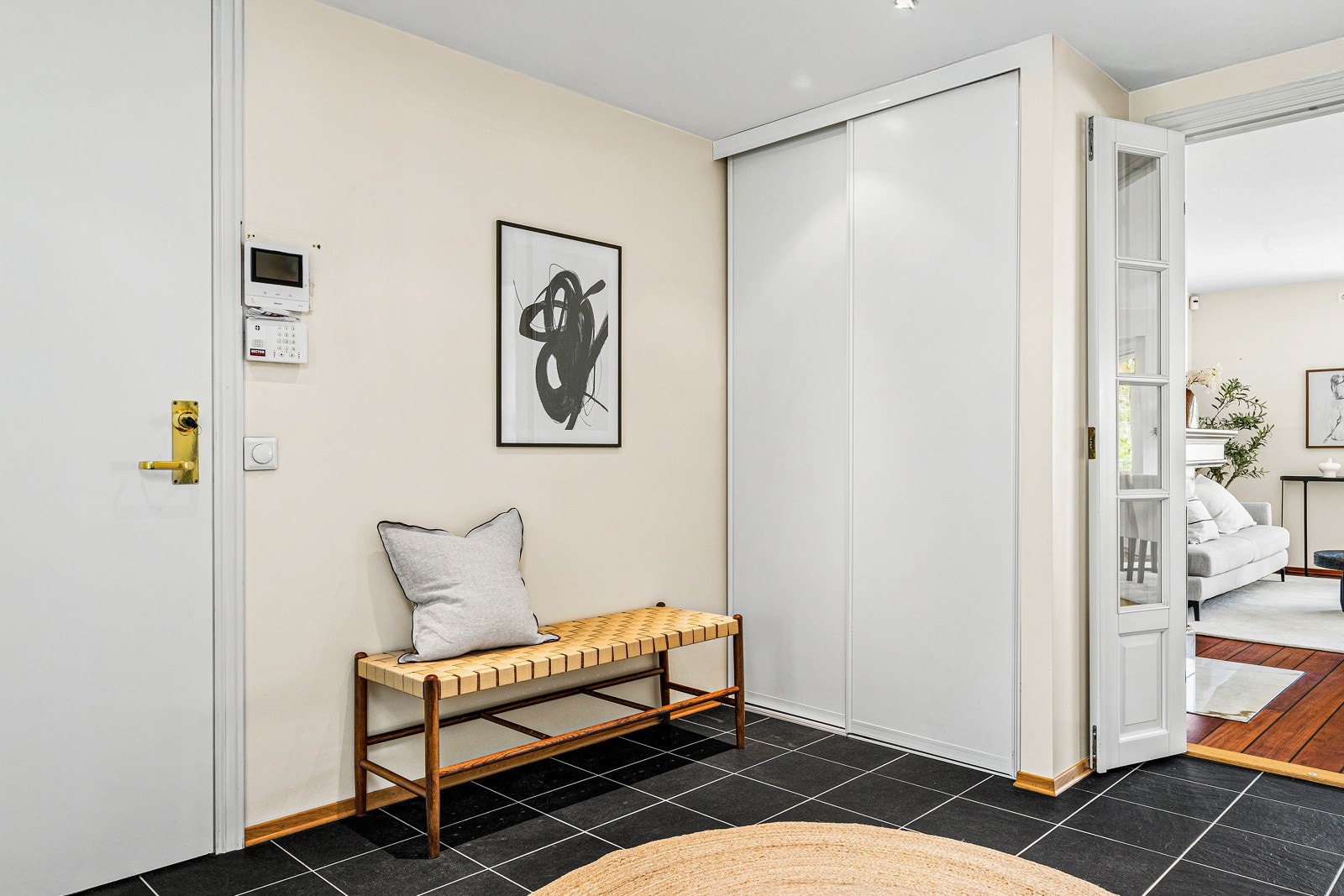 Langs den ene veggen finner du en praktisk skyvedørsgarderobe, som både skjuler yttertøy og sko på en ryddig måte og skaper en følelse av enda mer rom og lys. Galleribilde