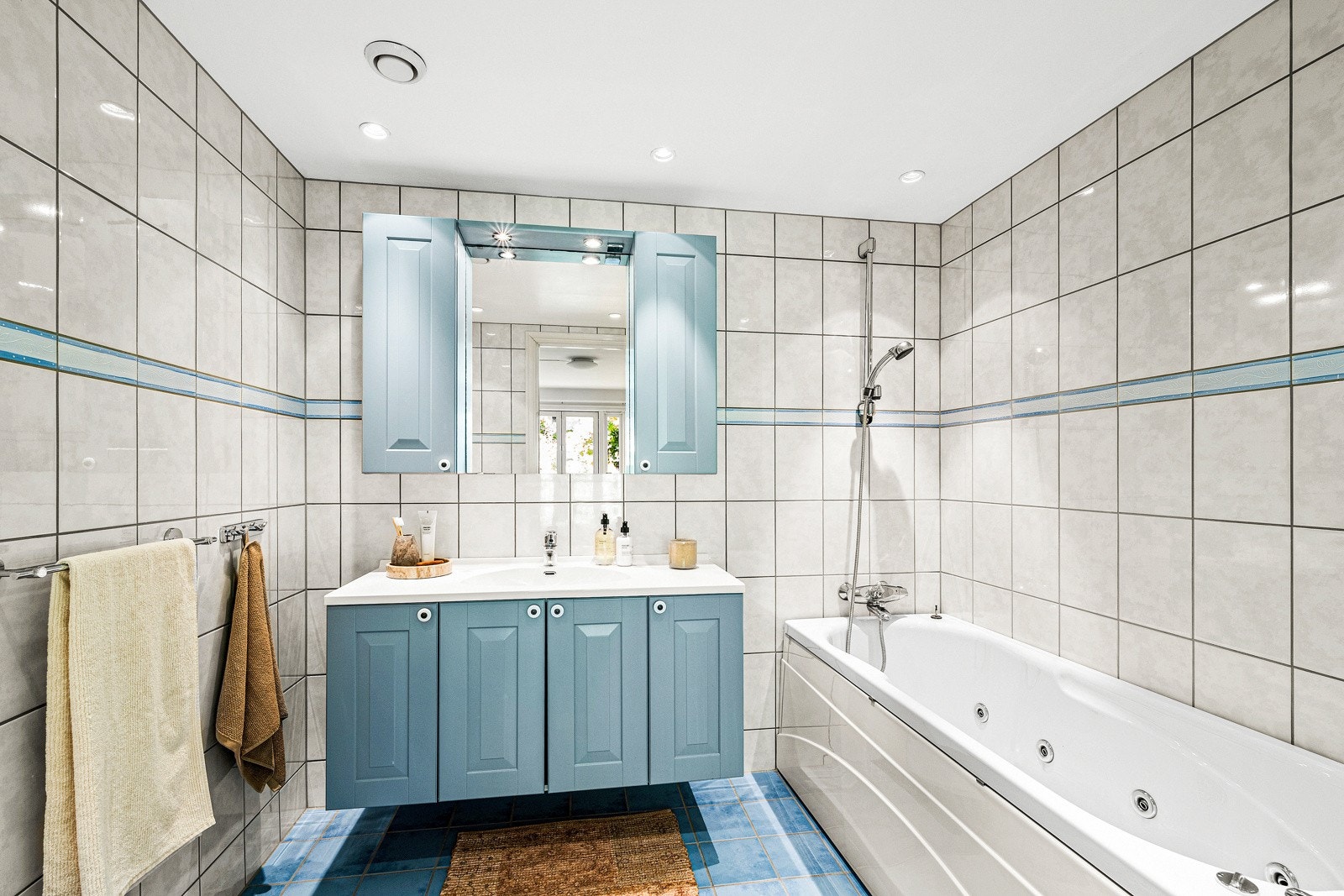 Romslig, flislagt bad med badekar og dusj. Servant med underskap og toalett. Downlights i tak med dimming. Galleribilde