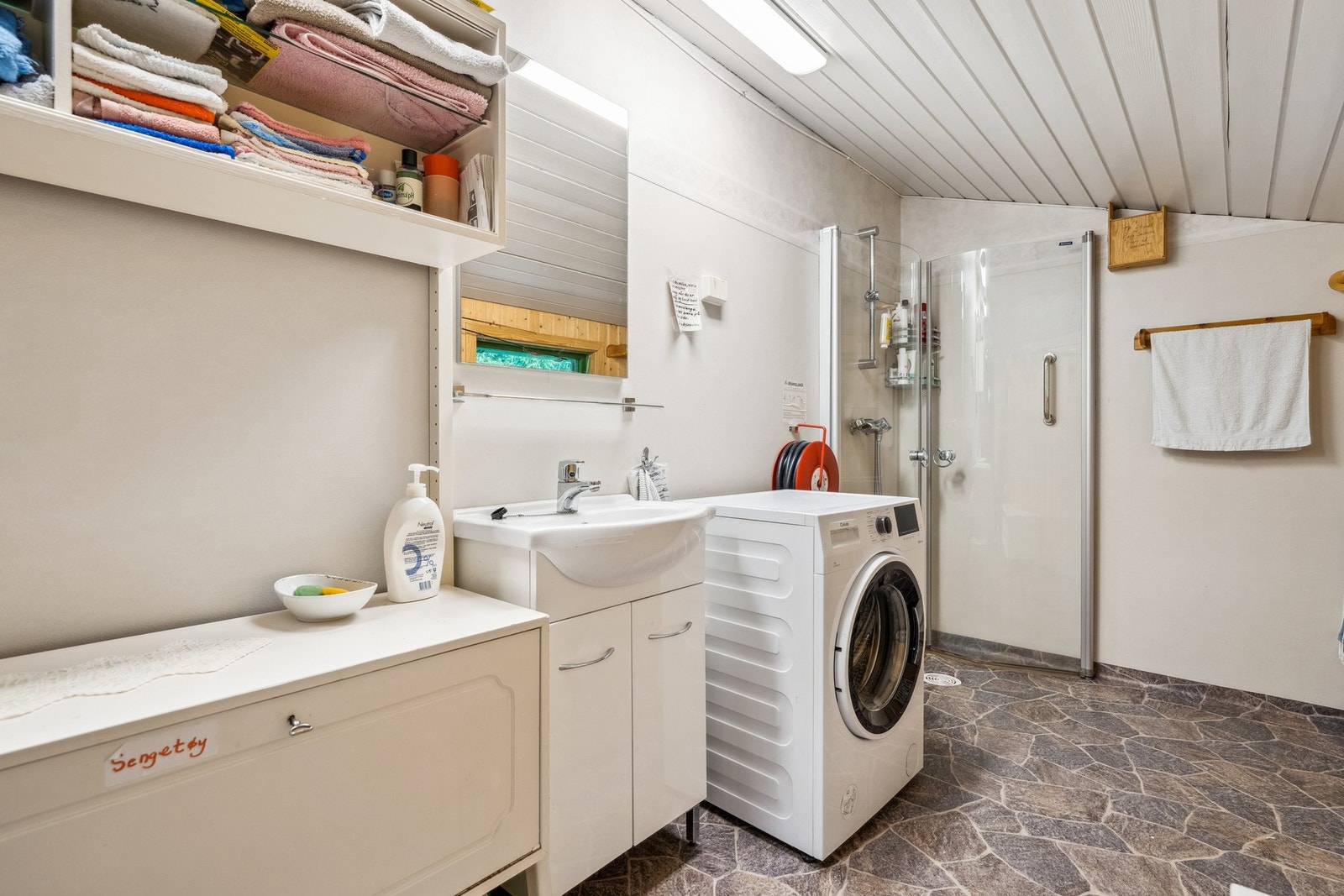 Badet har gulvbelegg med elektriske varmekabler, våtromstapet og panel på veggene, samt malt panel i himlingen Galleribilde