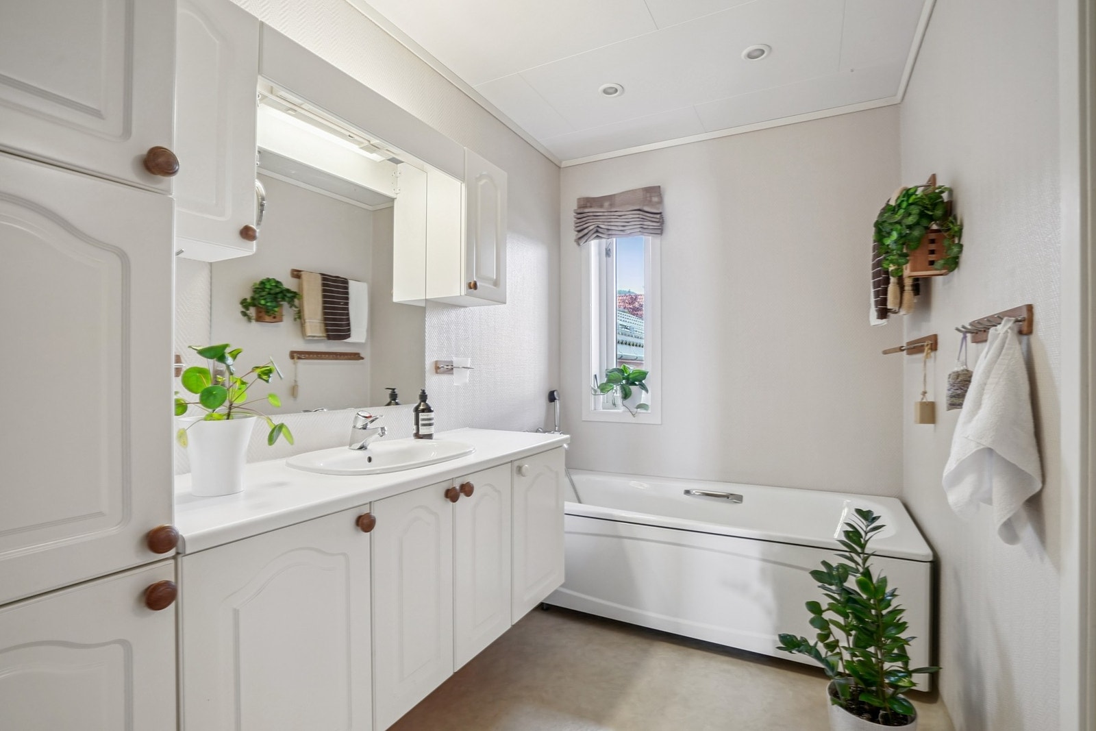 Innredet med baderomsinnredning, speil med belysning over, badekar og toalett. Galleribilde