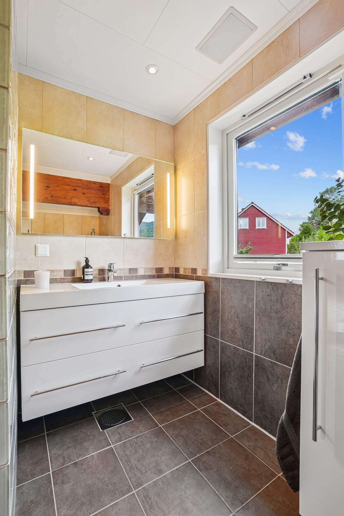 Badet er innredet med servantinnredning, speil med integrert belysning, vegghengt skap - Galleribilde