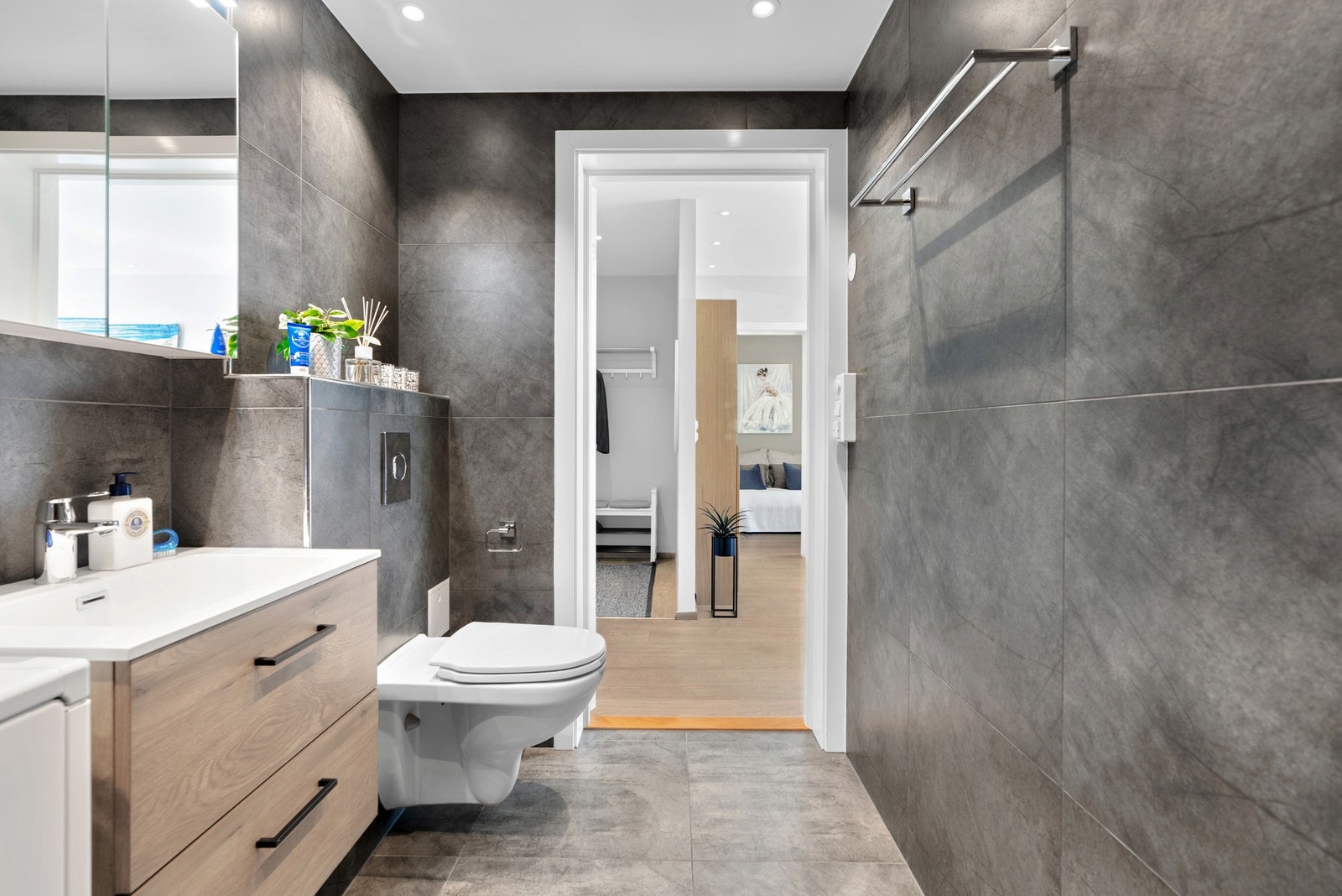 Vegghengt servantskap og ovenpåliggende servant med ett-greps armatur. Hylle og speil med belysning over og downlights i himling. Galleribilde