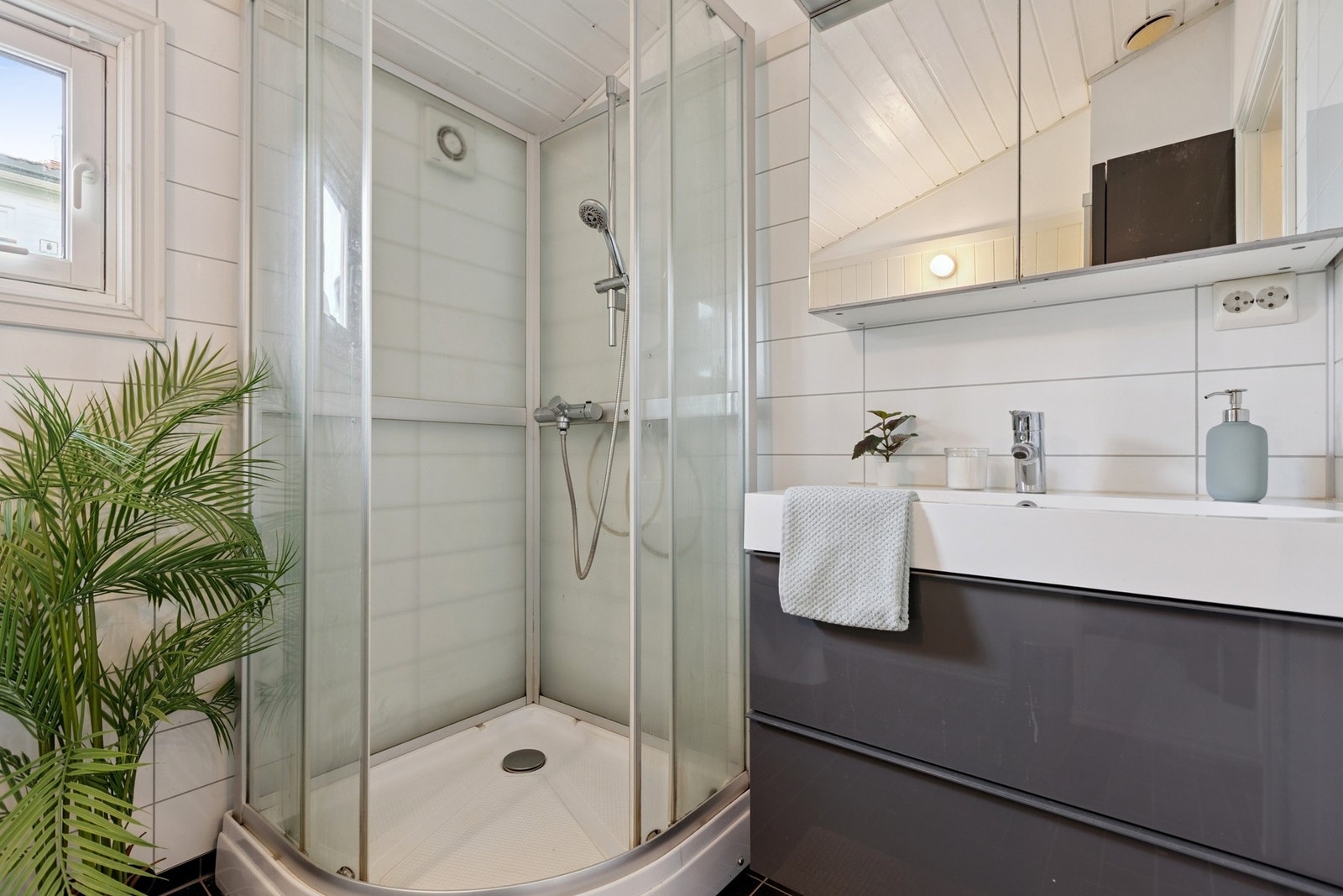 Baderommet er utstyrt med vegghengt servantinnredning, gulvstående toalett og dusjkabinett med dusjarmatur. Galleribilde