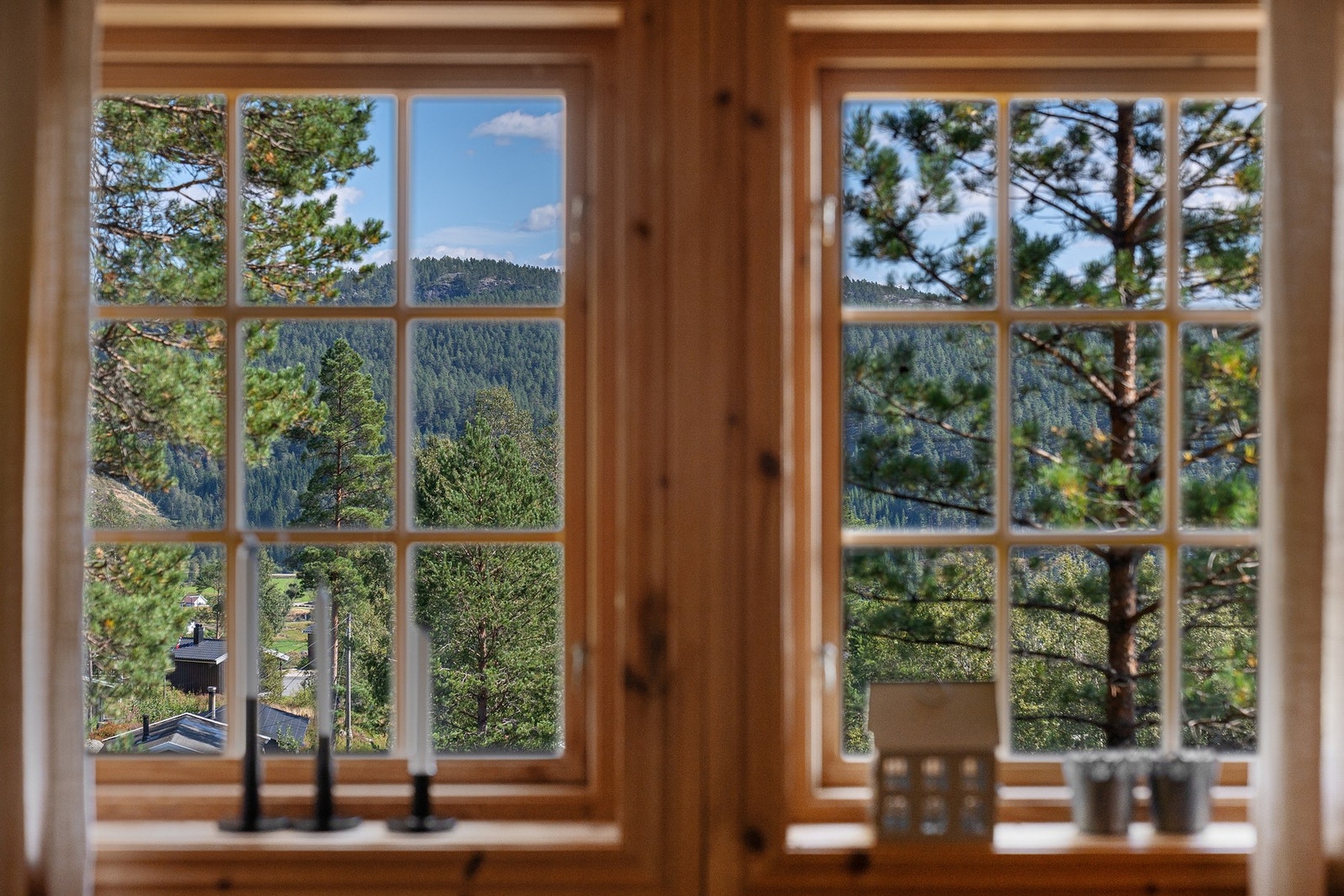 Utsikt gjennom vinduer mot skogkledde åser. Galleribilde